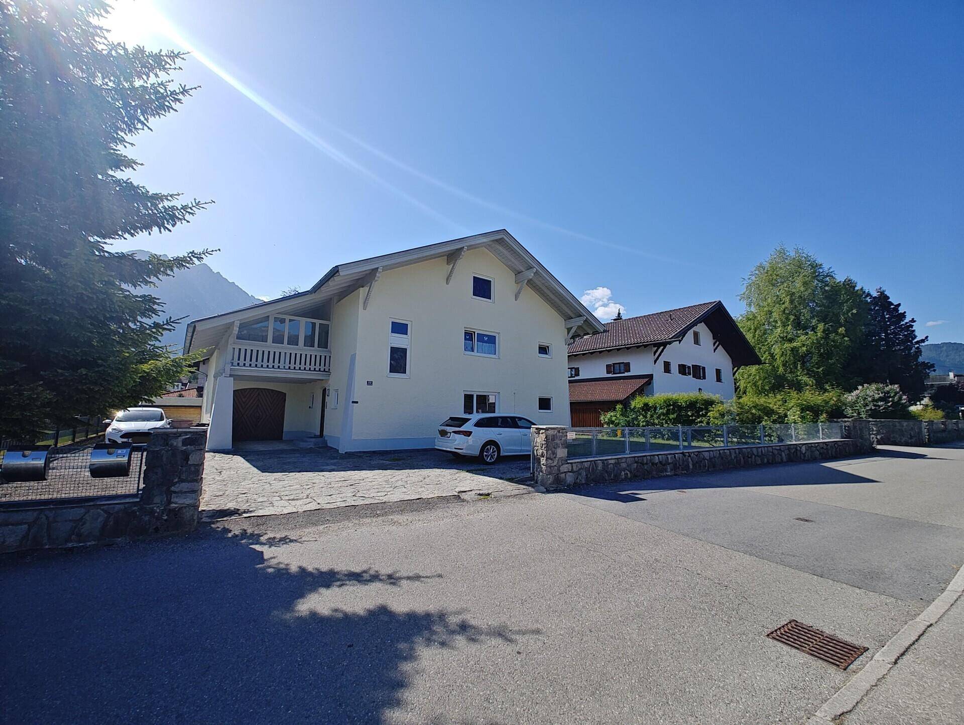 Vorderansicht des Hauses von der Straße aus mit Einfahrt und gepflegter Steinmauer.