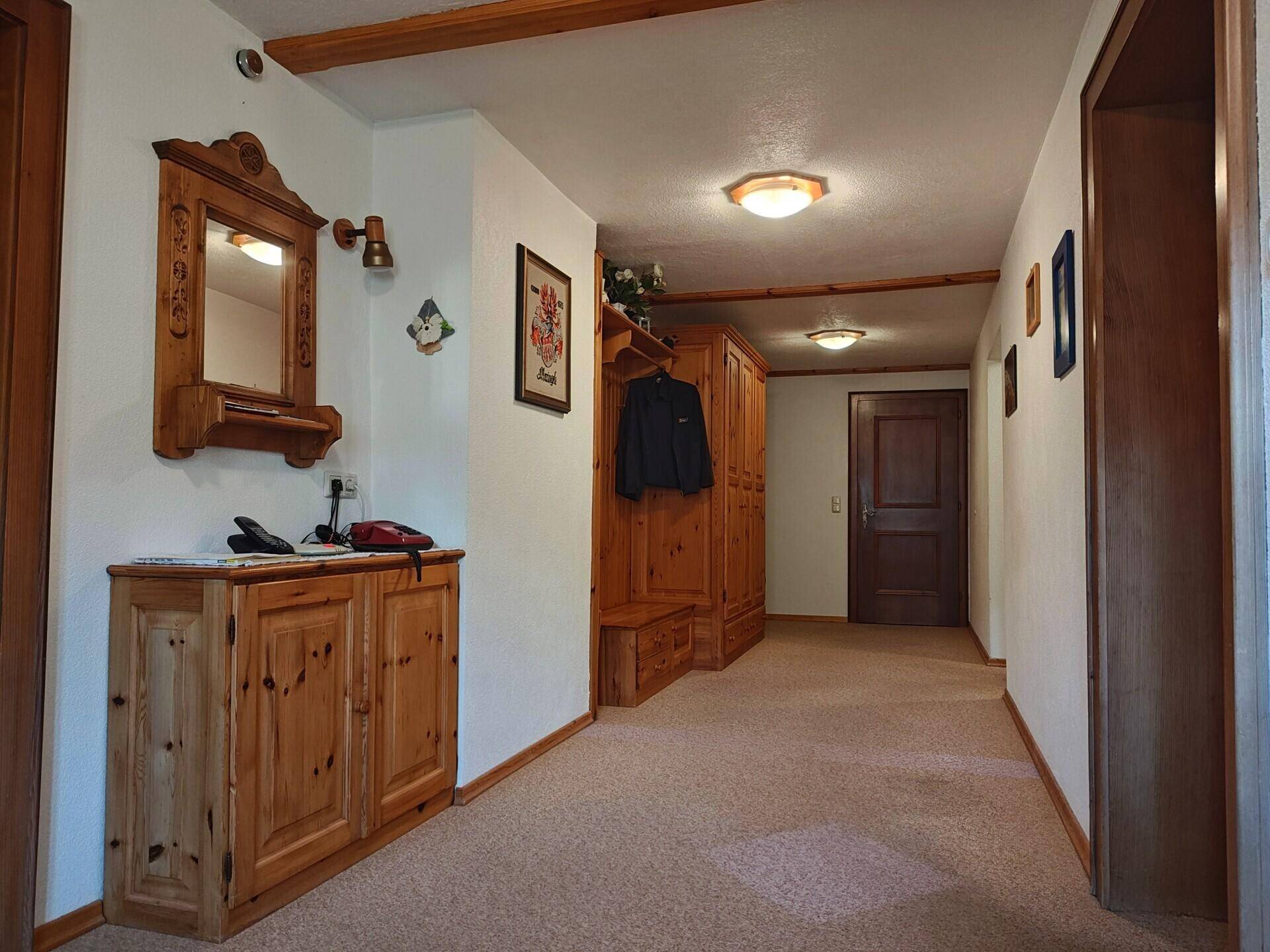 Heller Flur mit Holzmöbeln, Spiegel und Garderobe, bietet viel Stauraum.