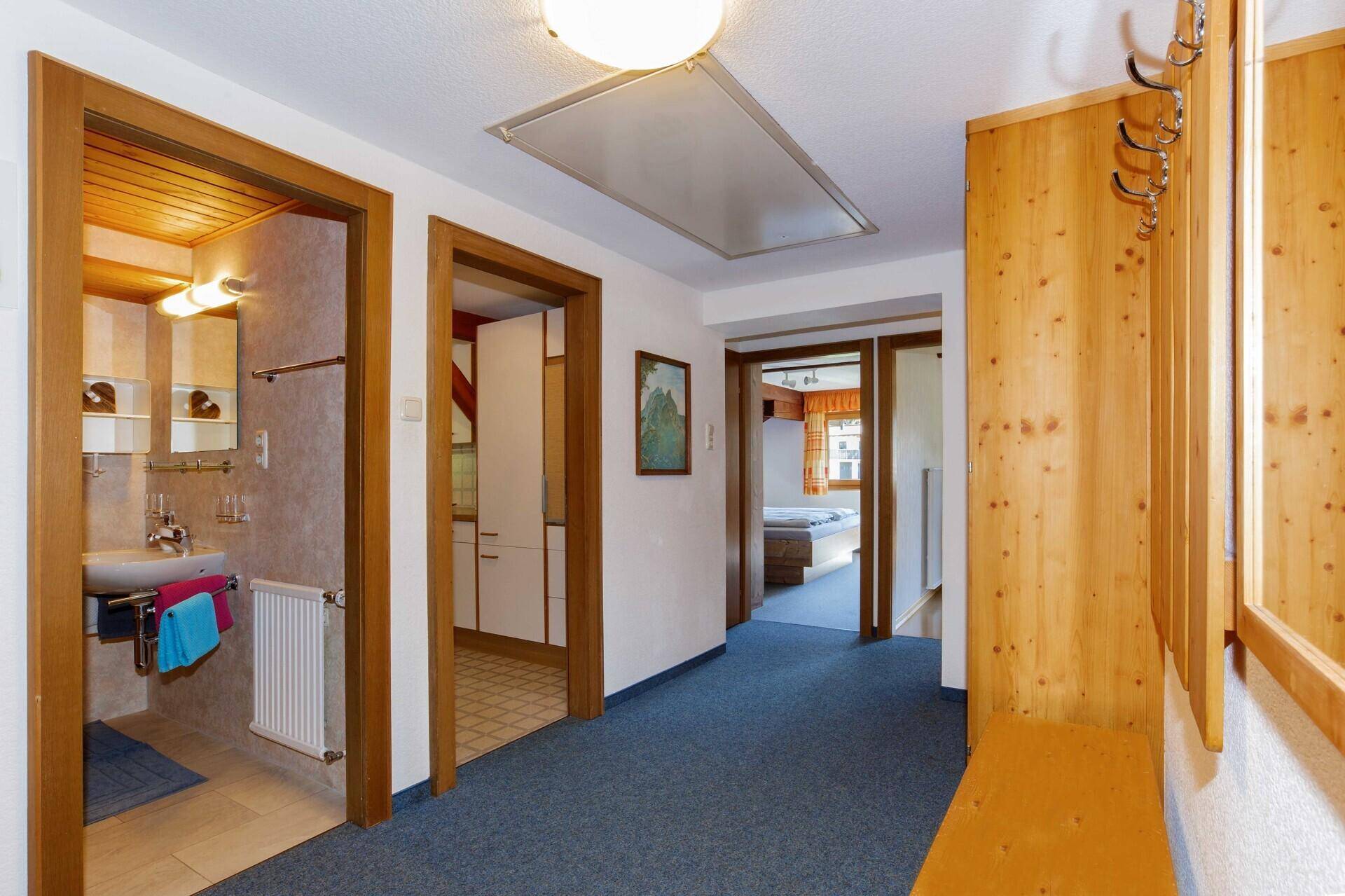 Heller Flur mit Teppichboden und Holzvertäfelung, verbindet verschiedene Räume.