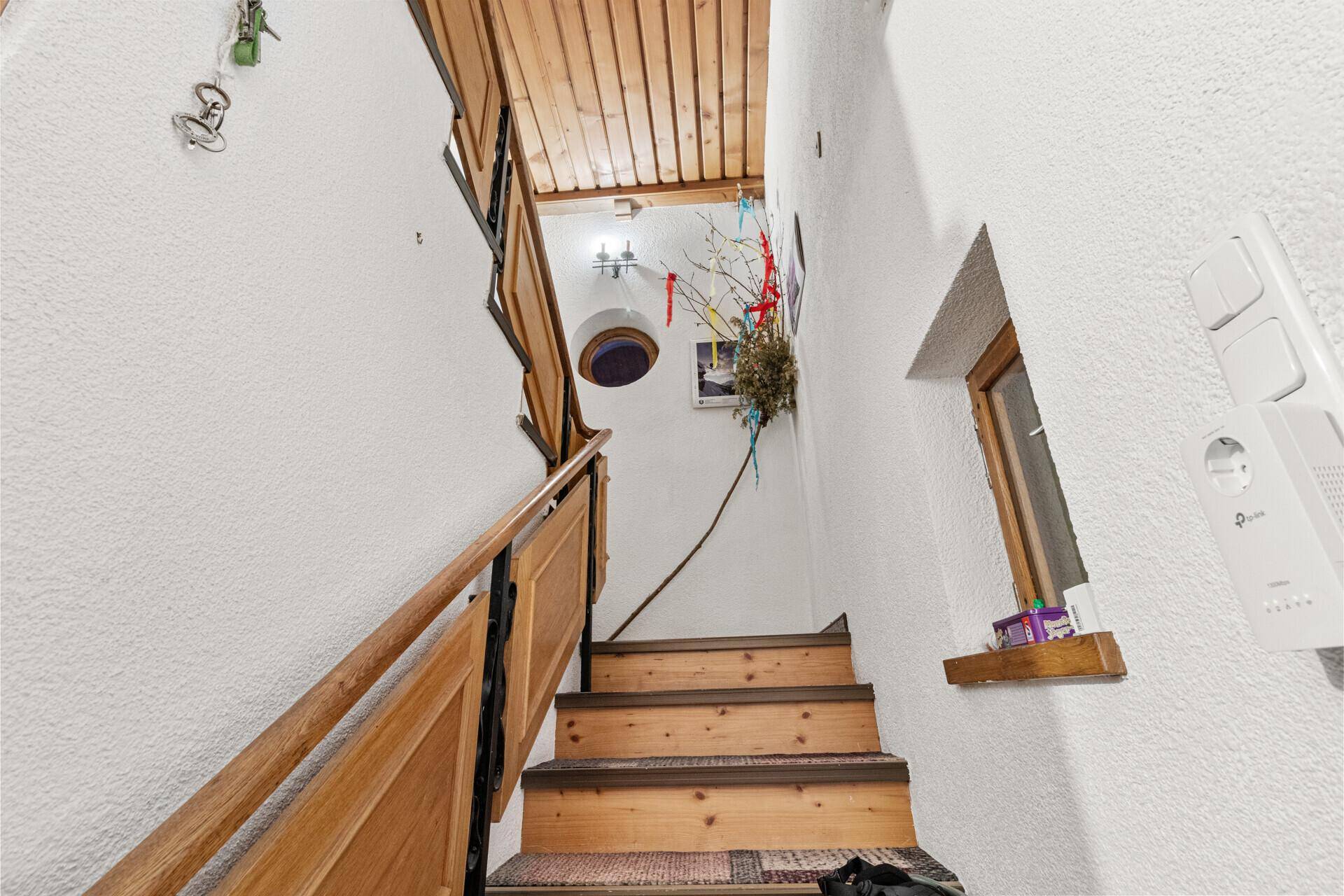 Holztreppe mit Teppichläufer und rustikalem Geländer, die zu den oberen Etagen führt.