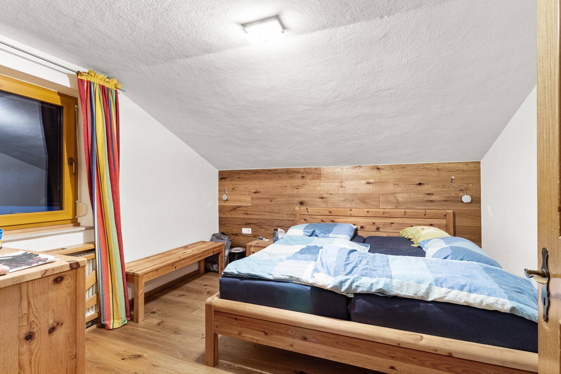 Gemütliches Schlafzimmer mit Holzbett, Holzwand und Holzboden, das eine warme Atmosphäre schafft.