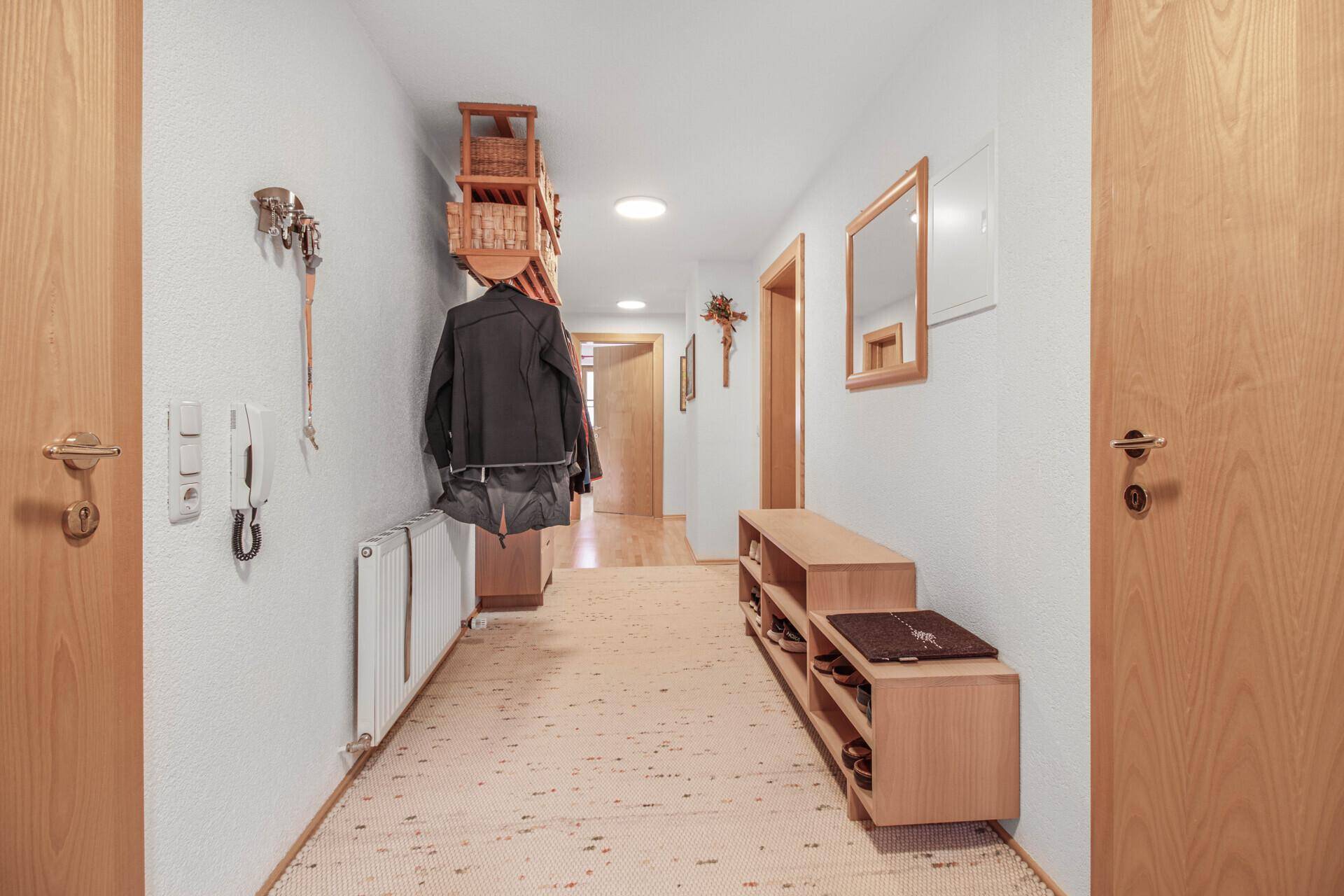 Einladender Flur mit Teppichboden, Holzmöbeln und Garderobe.
