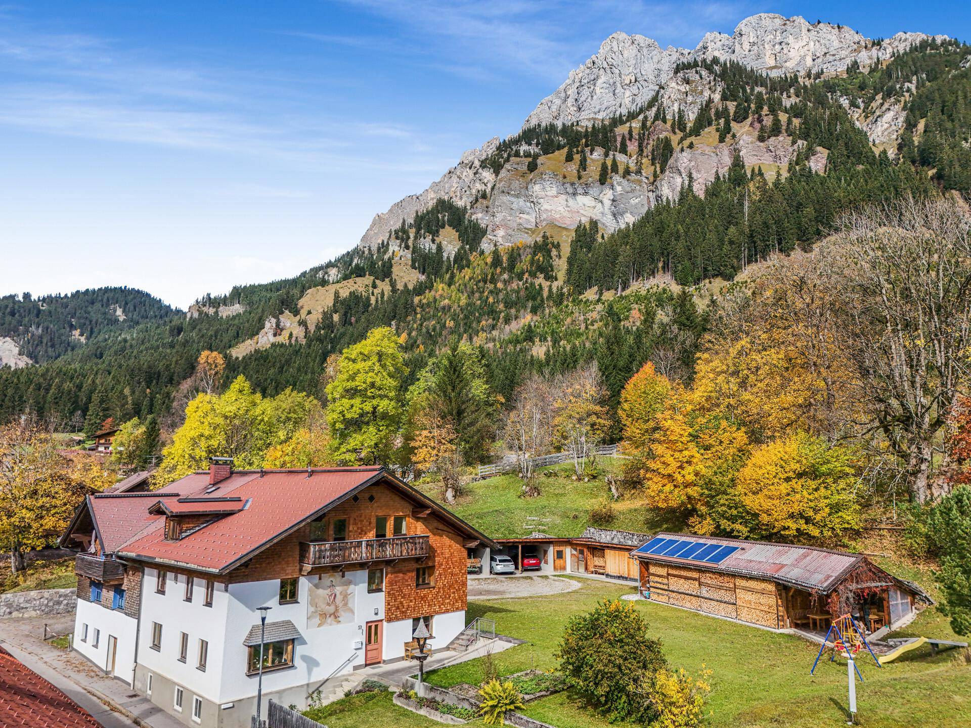 Traditionelles Haus mit Holzbalkonen und einem beeindruckenden Bergpanorama im Hintergrund.