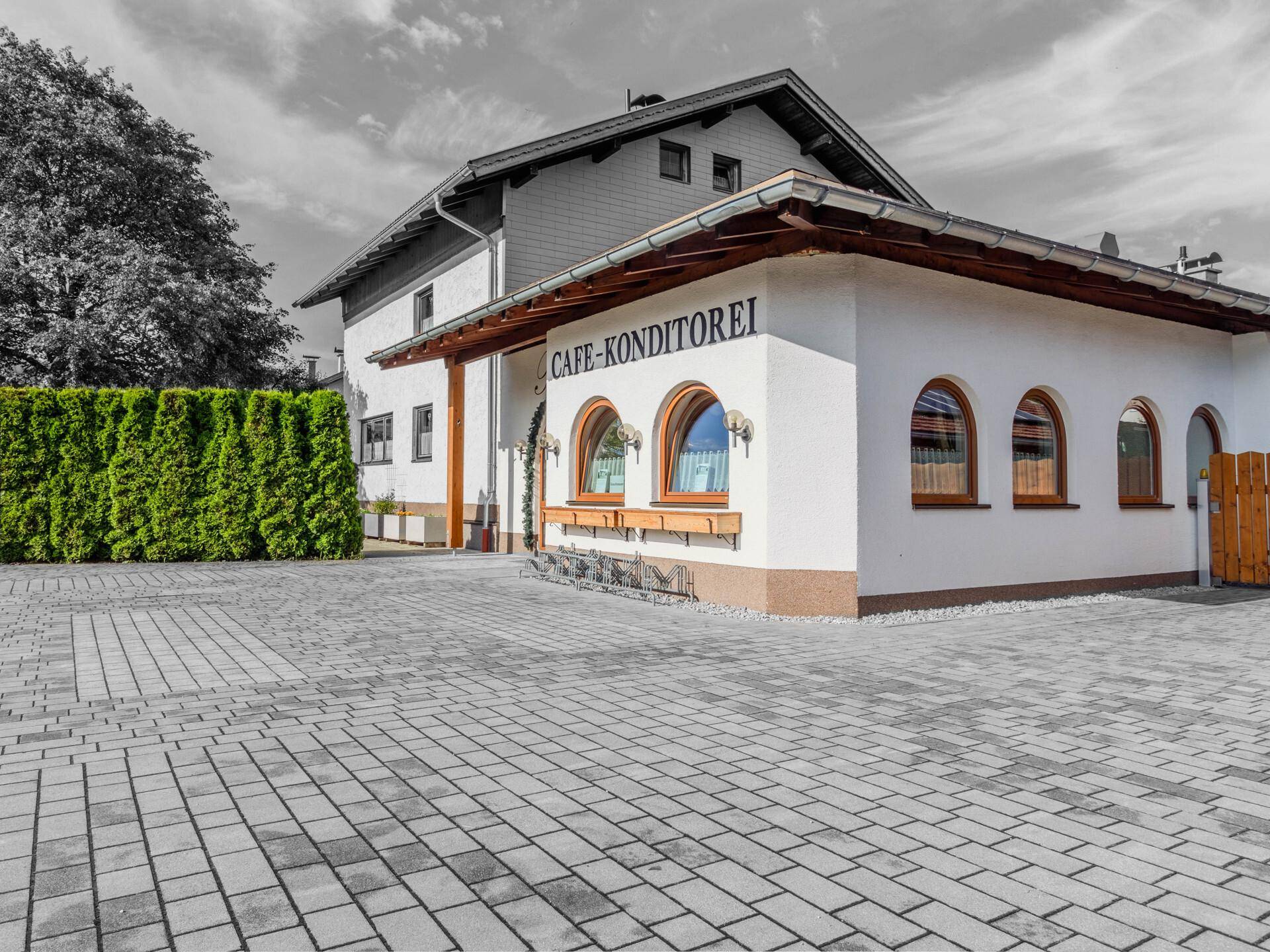 Die Außenansicht eines charmanten Gebäudes mit weißer Fassade, Rundbogenfenstern und gepflastertem Vorplatz.