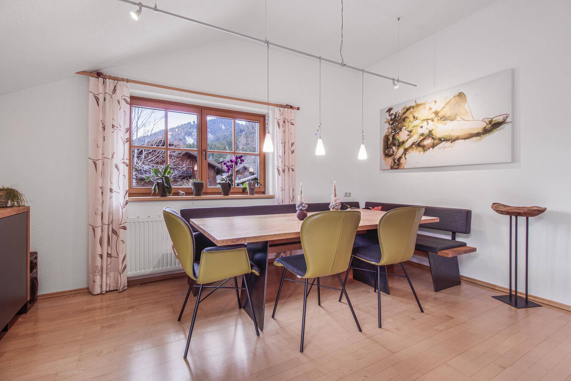 Gemütlicher Essbereich mit Holztisch, Sitzbank und Fensterblick ins Grüne.