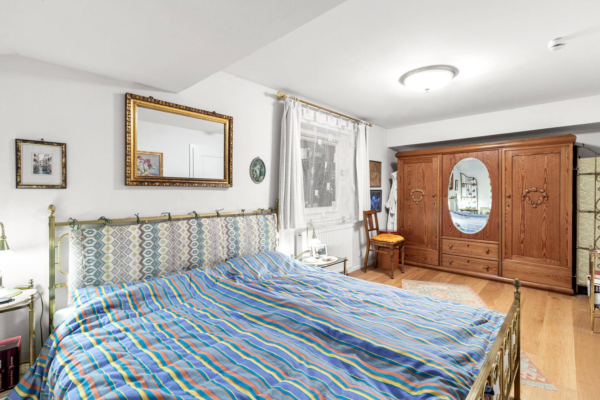 Schlafzimmer mit Doppelbett, Holzschrank und Holzboden.
