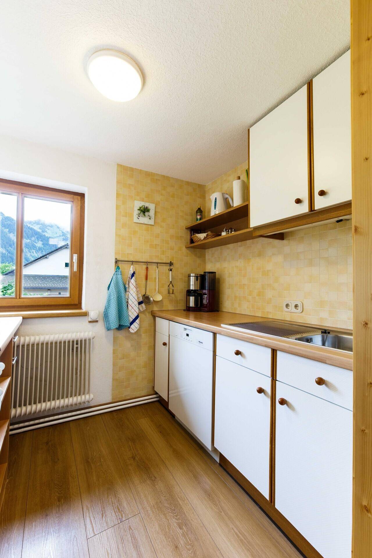 Helle Küche mit weißen Schränken, Holzarbeitsplatte und gelbem Fliesenspiegel.
