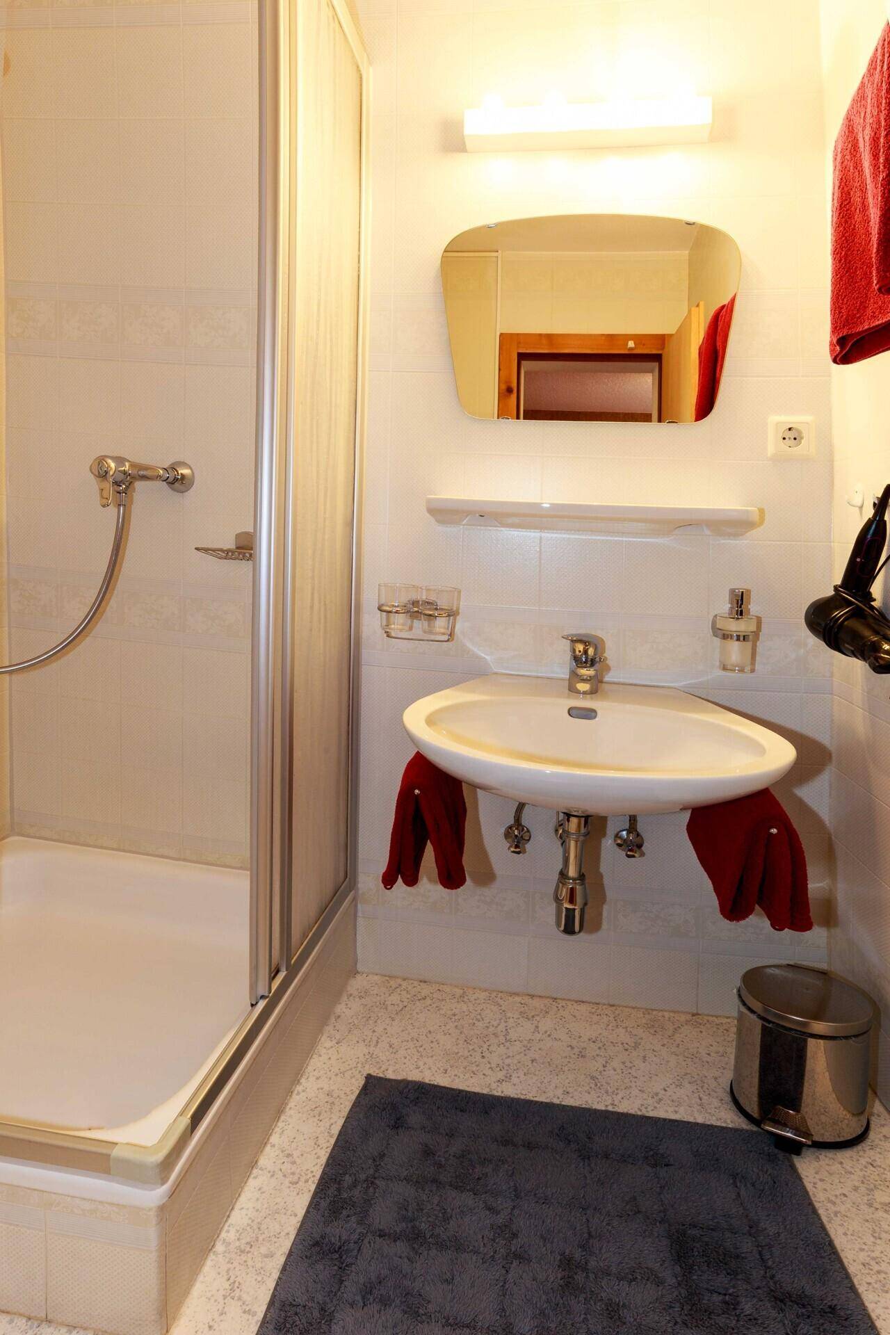 Funktionales Badezimmer mit Dusche, Waschbecken und Spiegel.