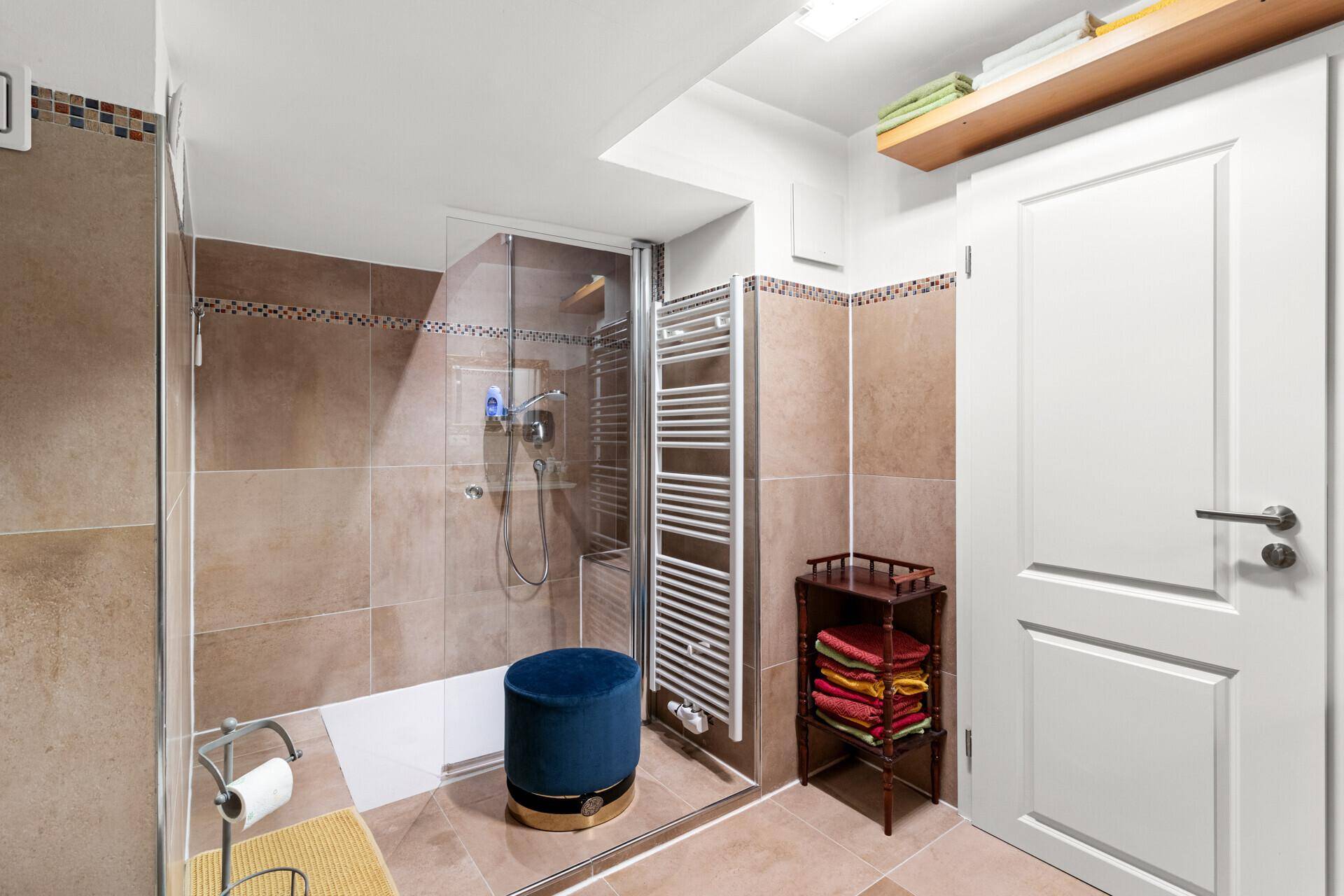 Modernes Badezimmer mit ebenerdiger Dusche, beheiztem Handtuchhalter und braunen Fliesen.