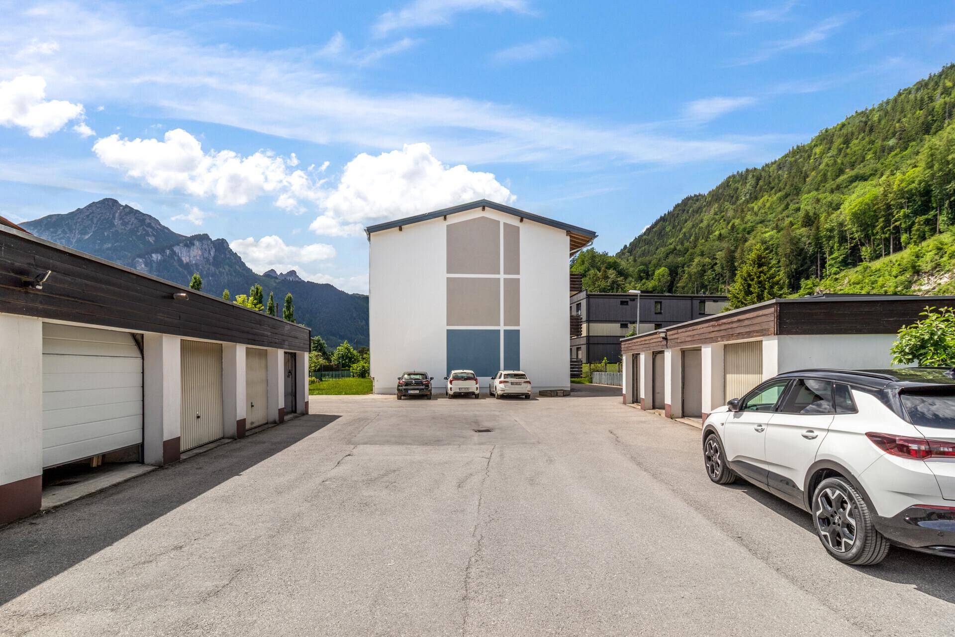 Parkplatzbereich mit Garagen und Autos vor der Kulisse der umliegenden Berge.