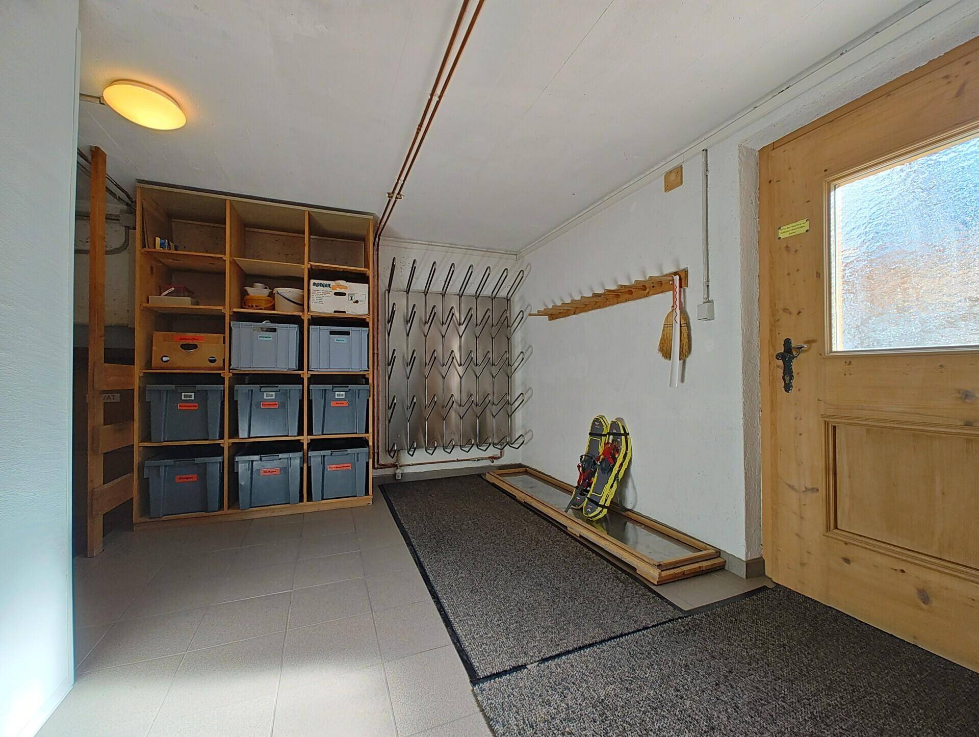 Praktischer Abstellraum mit Skischuhhaltern und Regalen für Sportausrüstung.