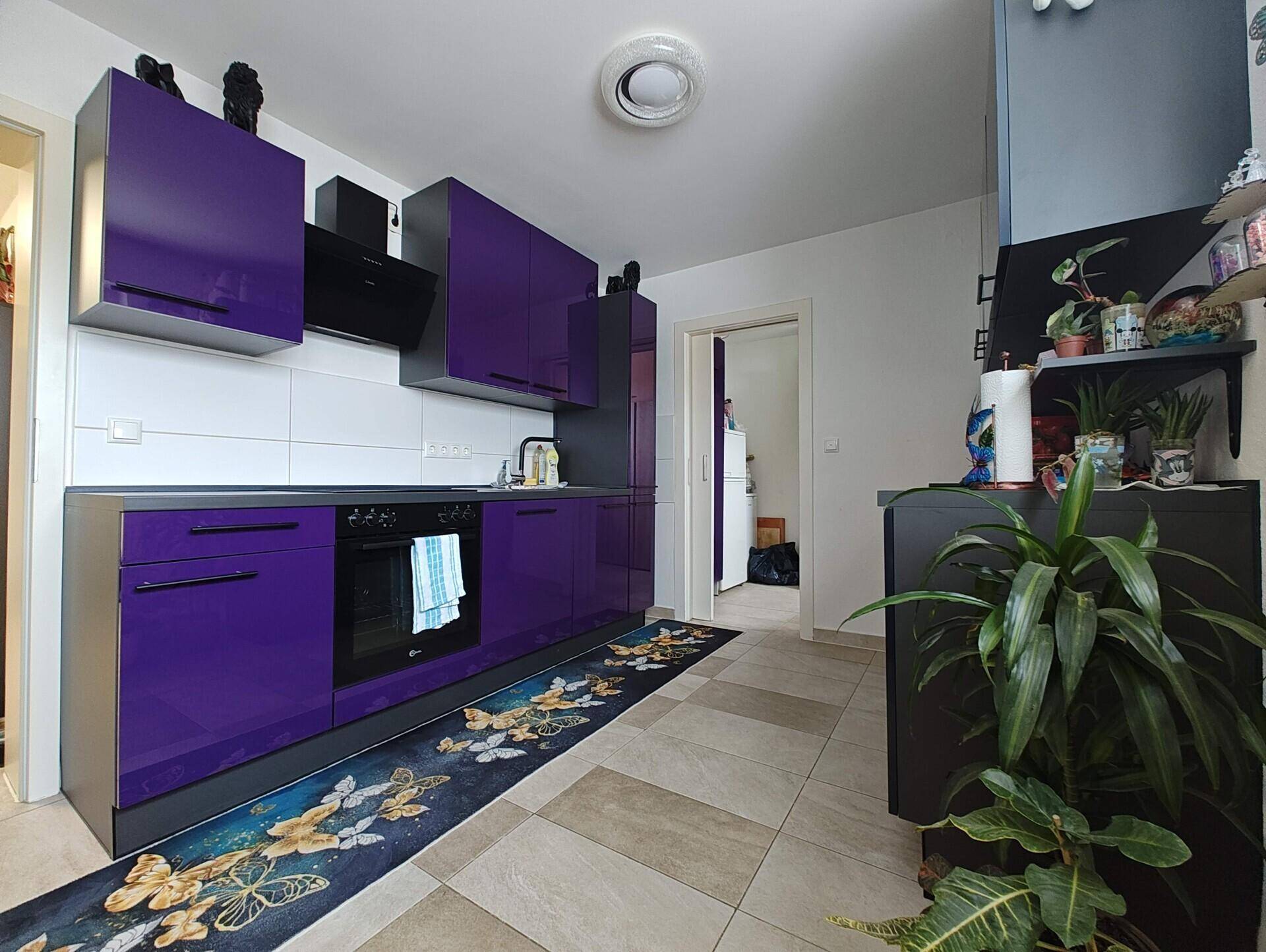 Moderne Küche mit auffälligen violetten Schränken und Fliesenboden.