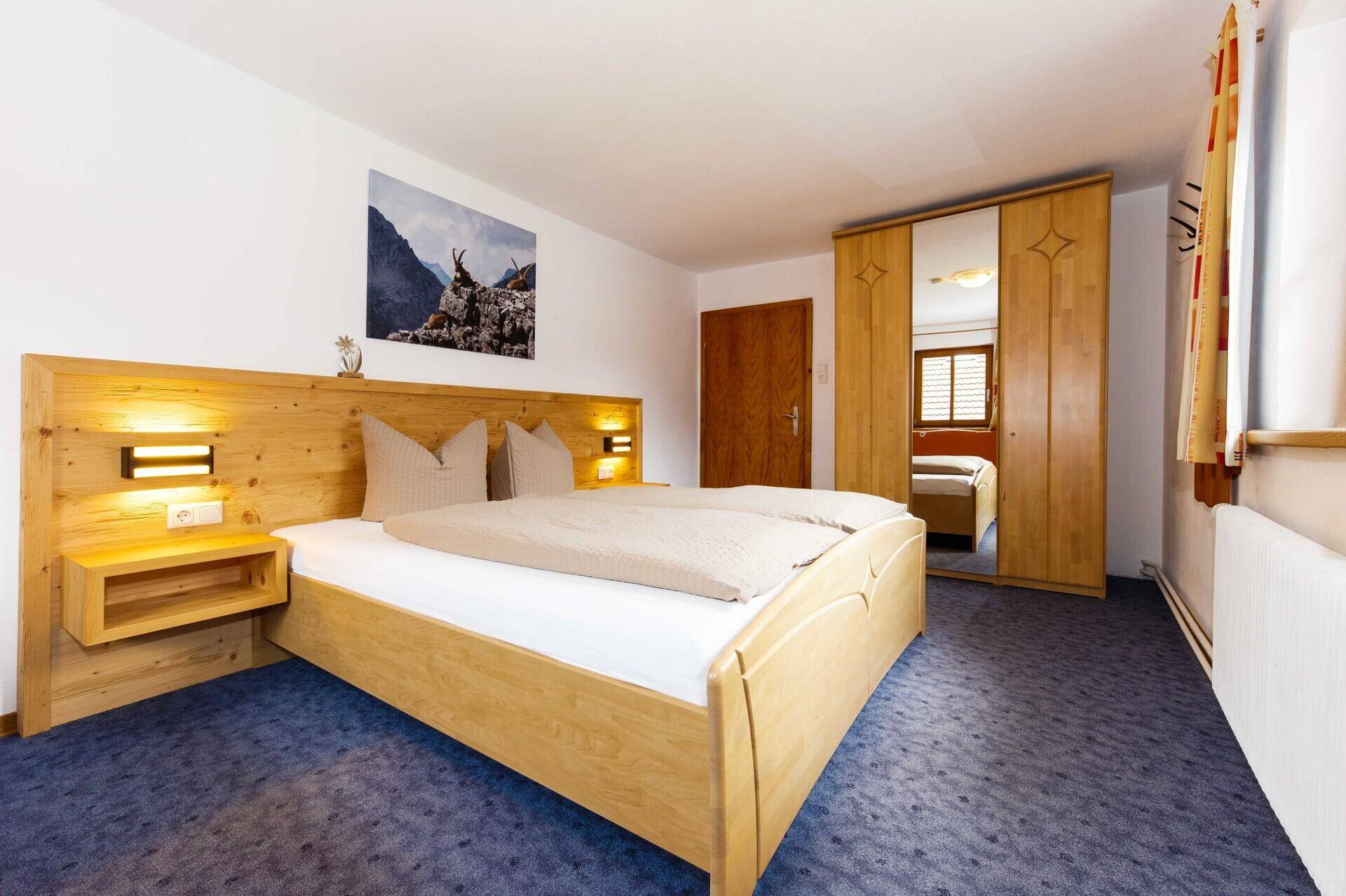 Geräumiges Schlafzimmer mit Holzbett, Spiegelschrank und Teppichboden.