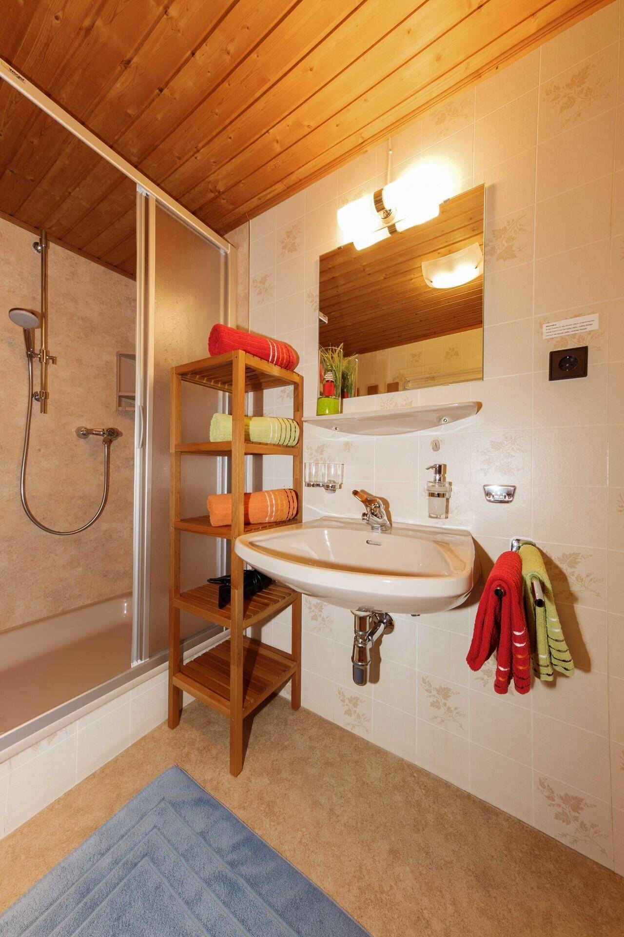 Funktionales Badezimmer mit Dusche, Waschbecken und Holzdecke.