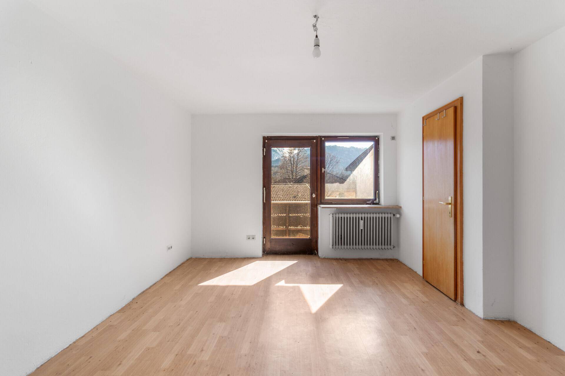 Heller Wohnraum mit Laminatboden und direktem Zugang zu einem Balkon.