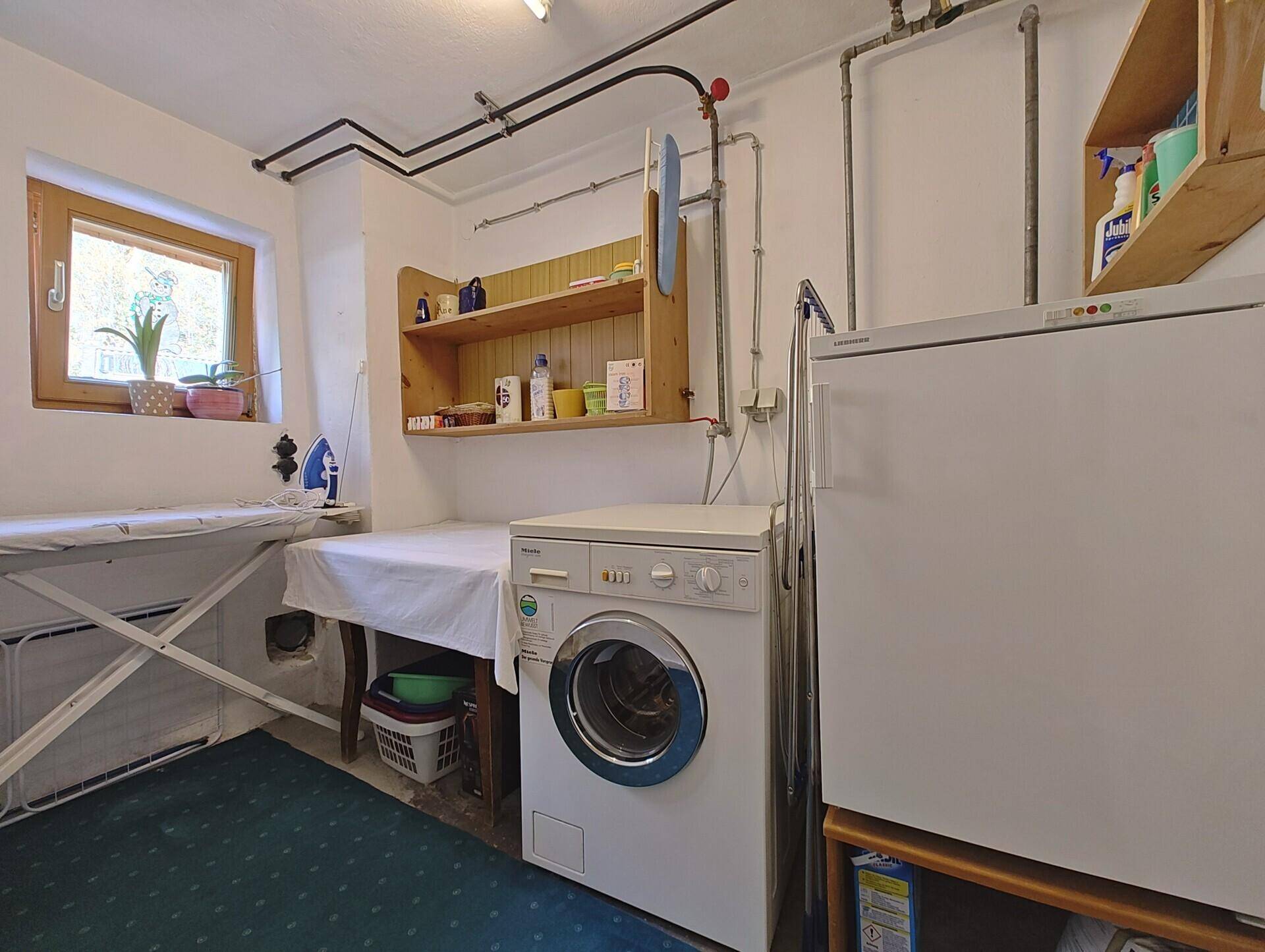 Praktischer Hauswirtschaftsraum mit Waschmaschine, Bügelbrett und Stauraum.
