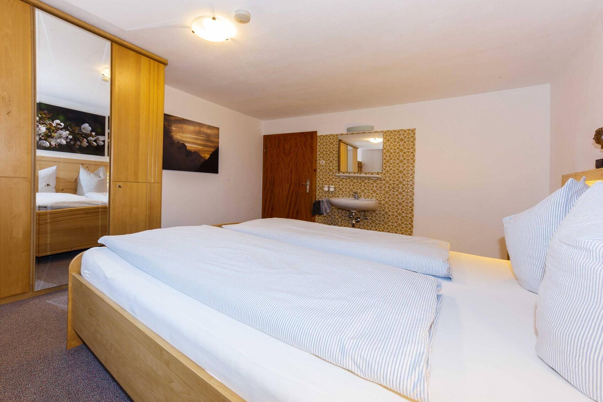 Schlafzimmer mit Holzbett, integriertem Waschbecken und Spiegelschrank.