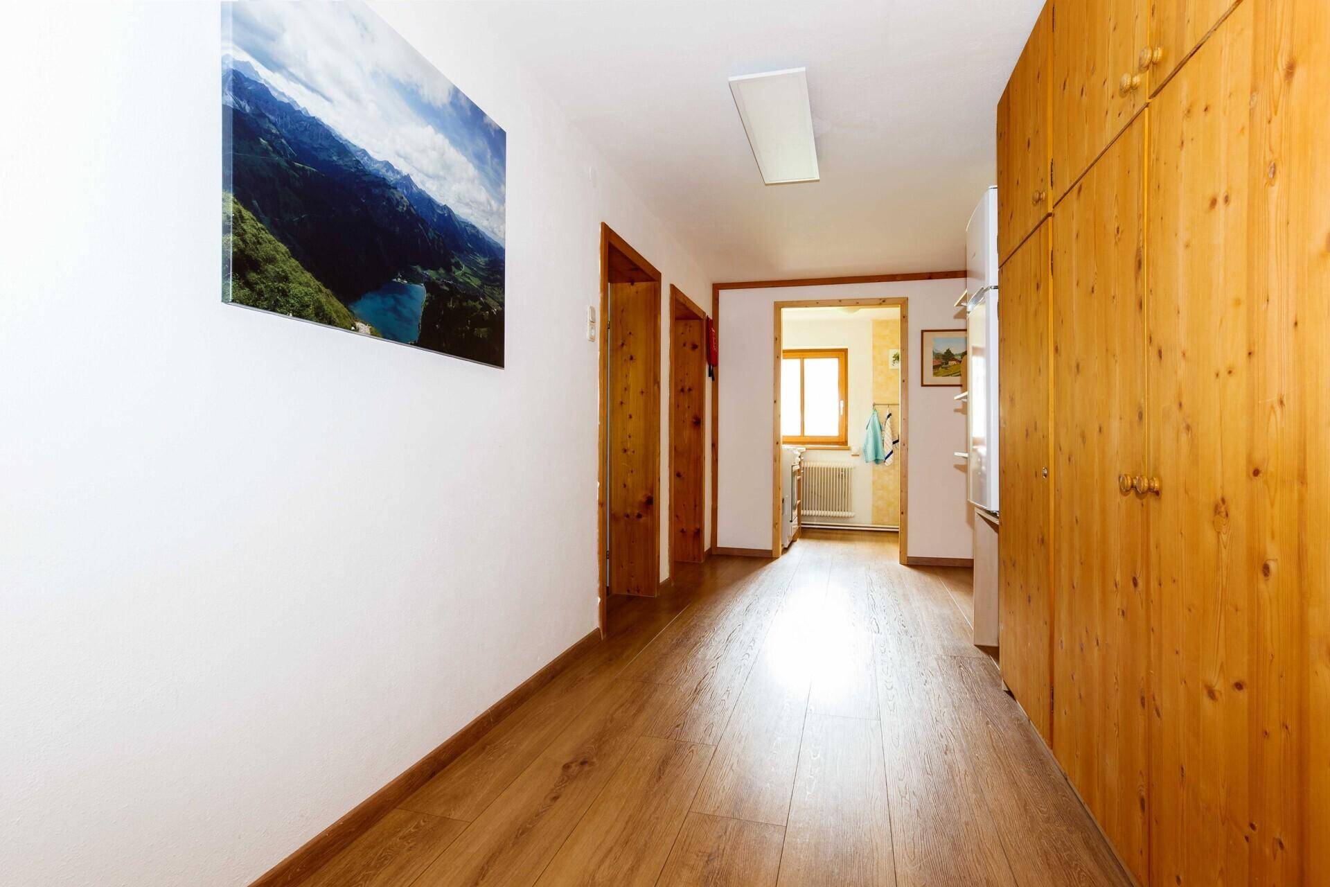 Langer Flur mit Holzboden und praktischen Einbauschränken.