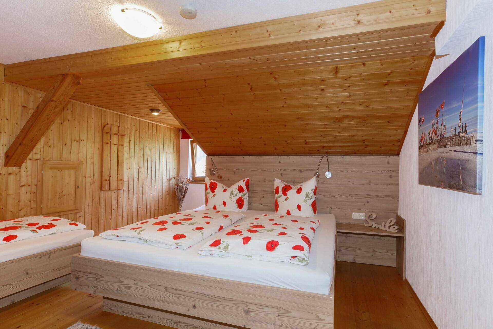 Rustikales Schlafzimmer mit zwei Holzbetten, sichtbaren Holzbalken und Holzvertäfelung.