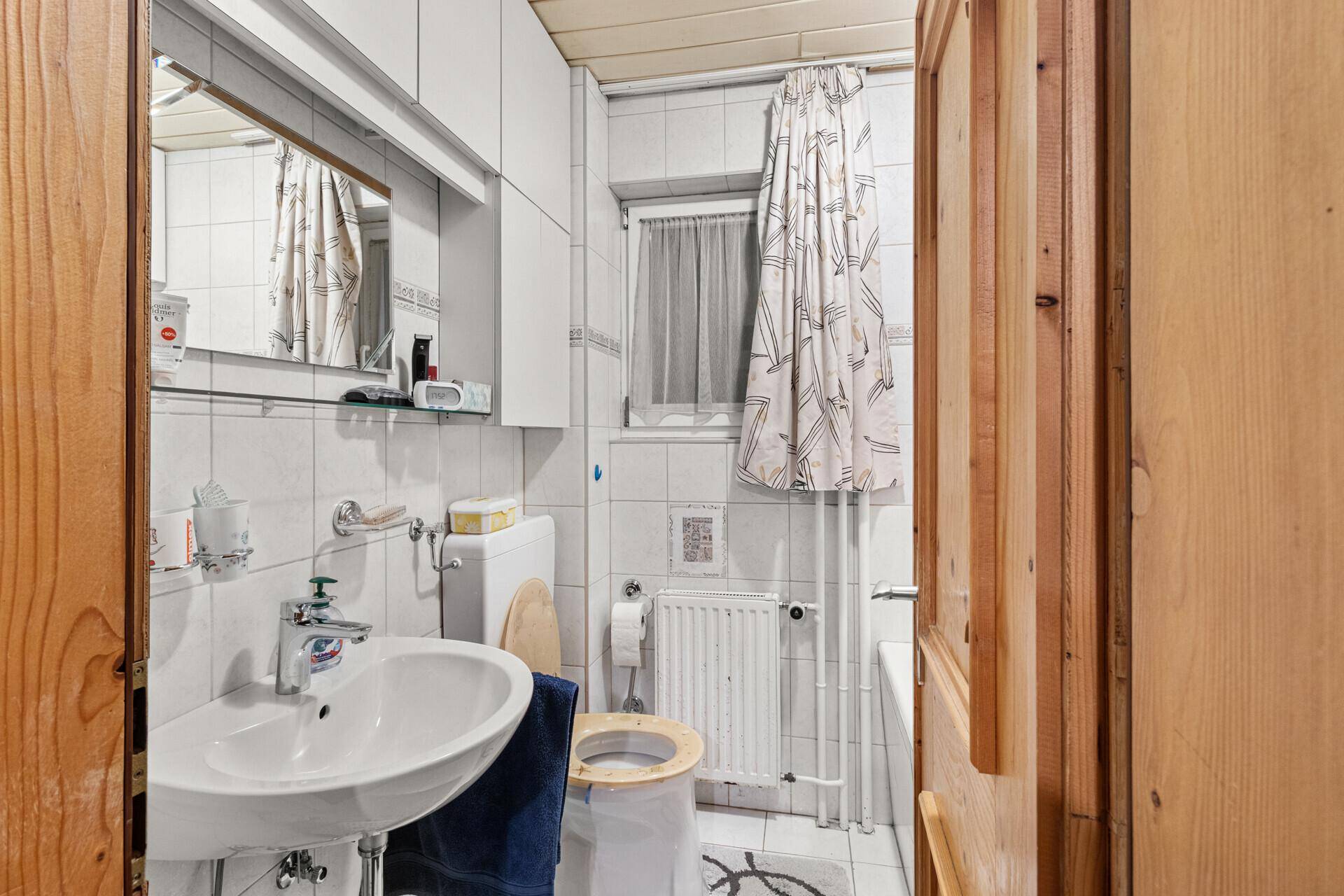 Helles Badezimmer mit Badewanne, WC und Waschbecken, das eine praktische Einrichtung bietet.