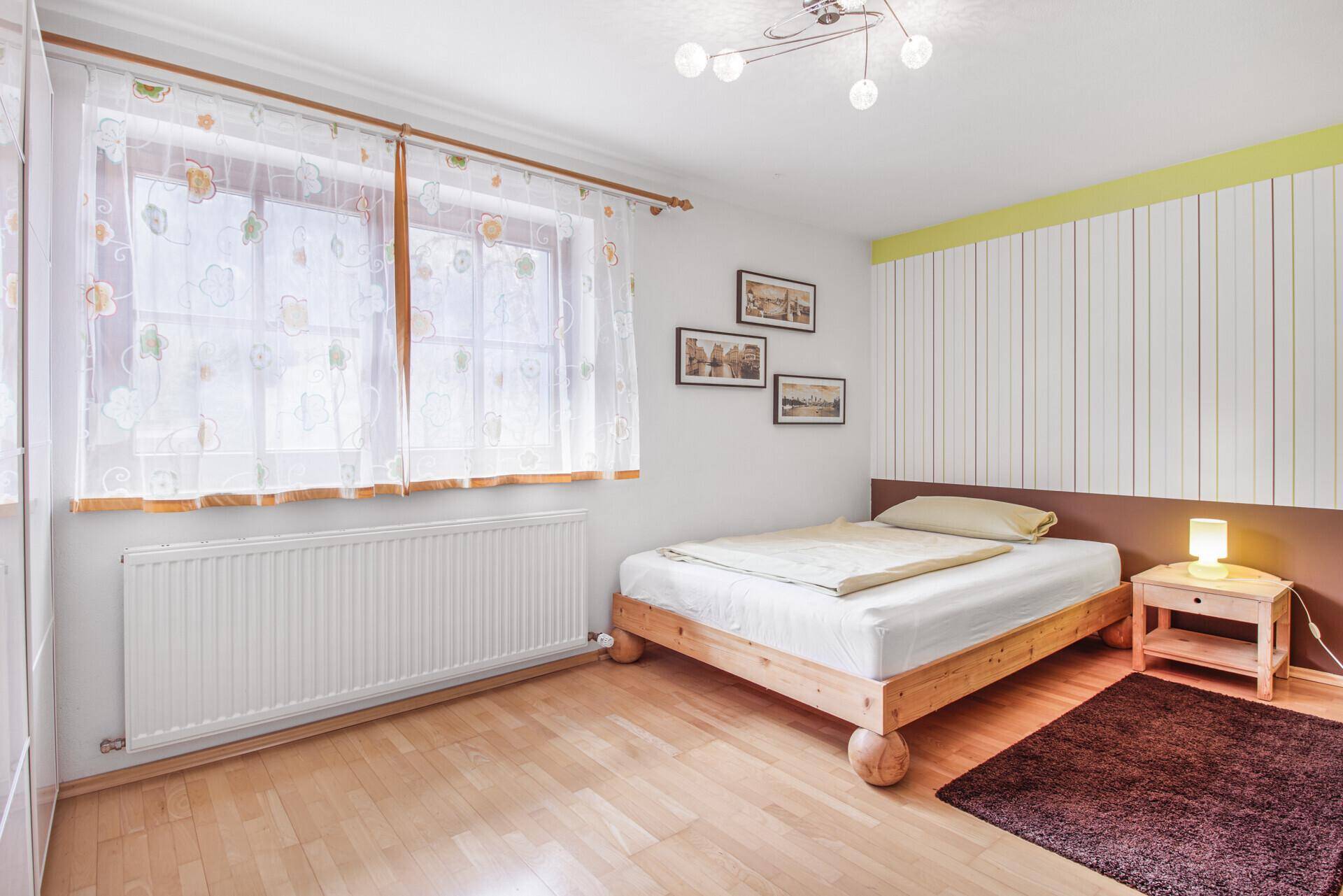 Freundliches Schlafzimmer mit Einzelbett, hellen Wänden und Fenster für Tageslicht.
