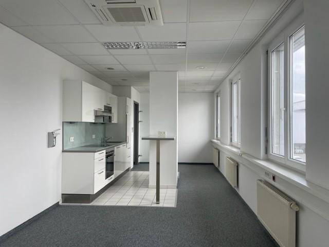 Modernes Büro mit integrierter Küchenzeile, Teppichboden und Klimaanlage an der Decke.