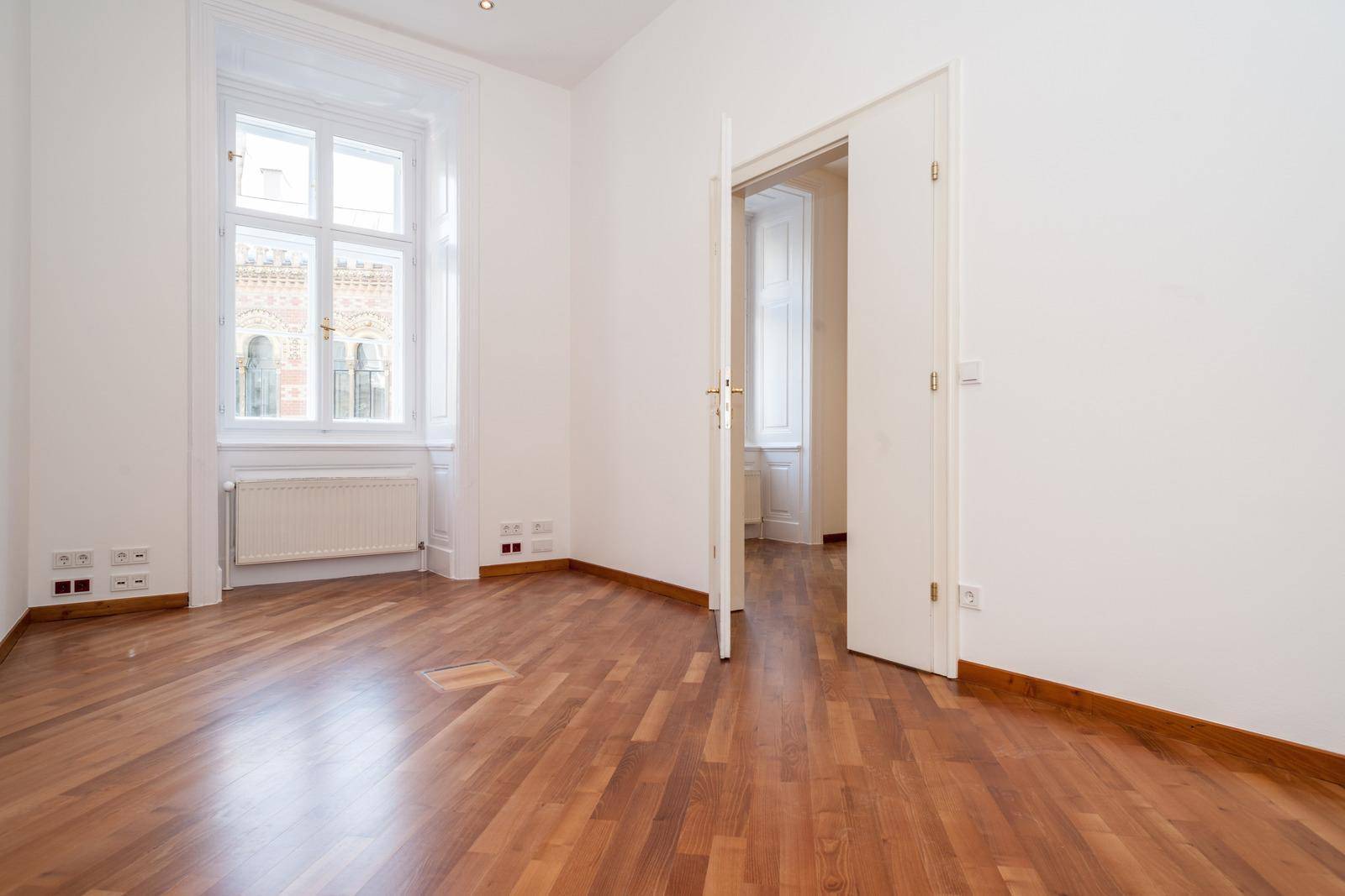 Geräumiger Büroraum mit Holzboden und hohen Fenstern, die eine angenehme Atmosphäre schaffen.
