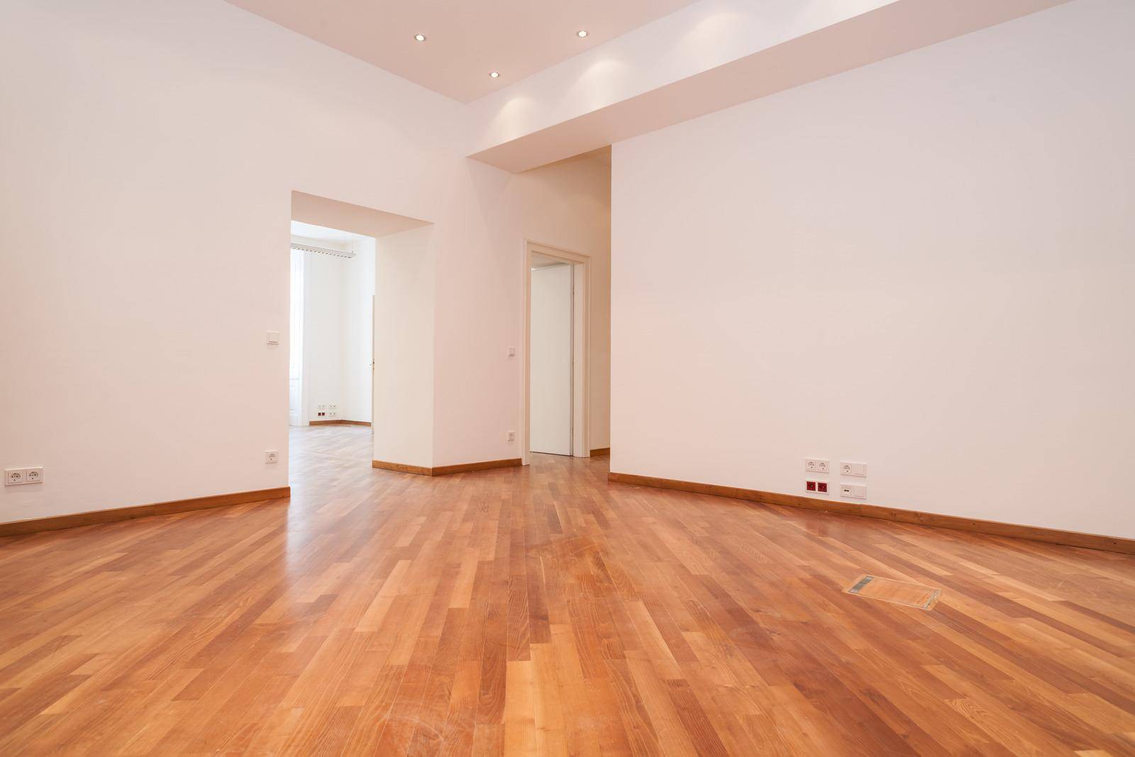Großer, heller Raum mit Holzboden und integrierten Deckenleuchten, bereit zur individuellen Gestaltung.