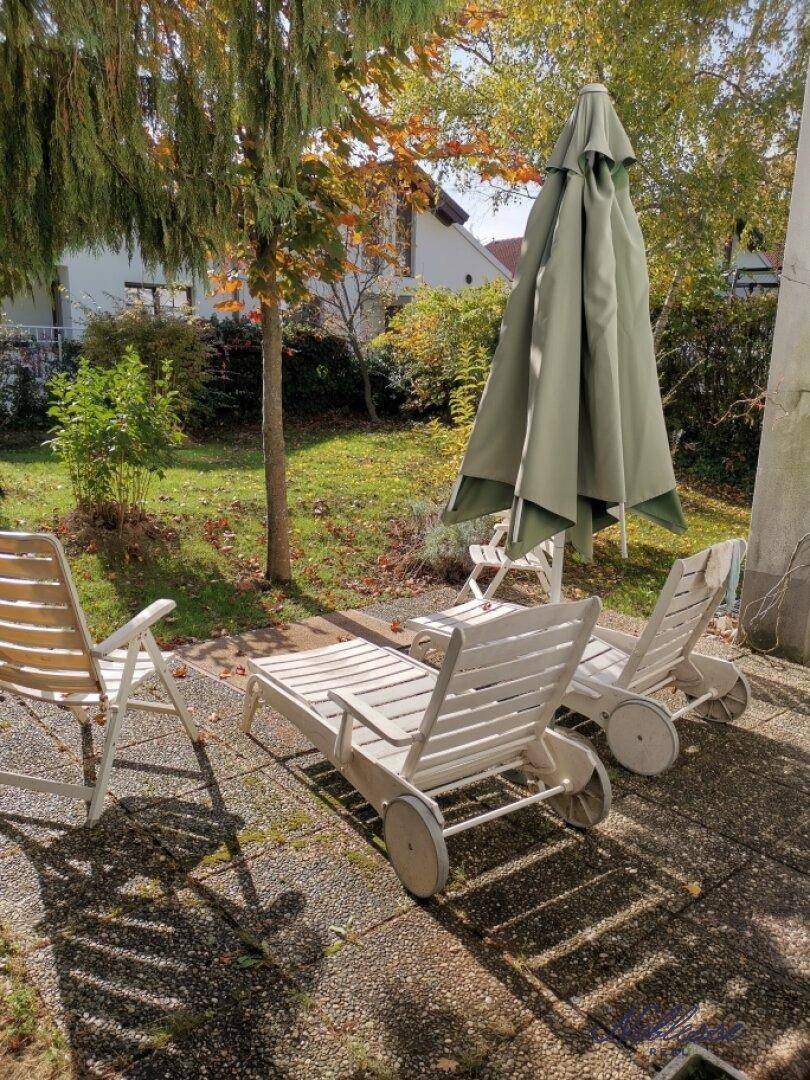 Sonniger Gartenbereich mit Liegestühlen und Sonnenschirm, ideal zum Entspannen im Freien.