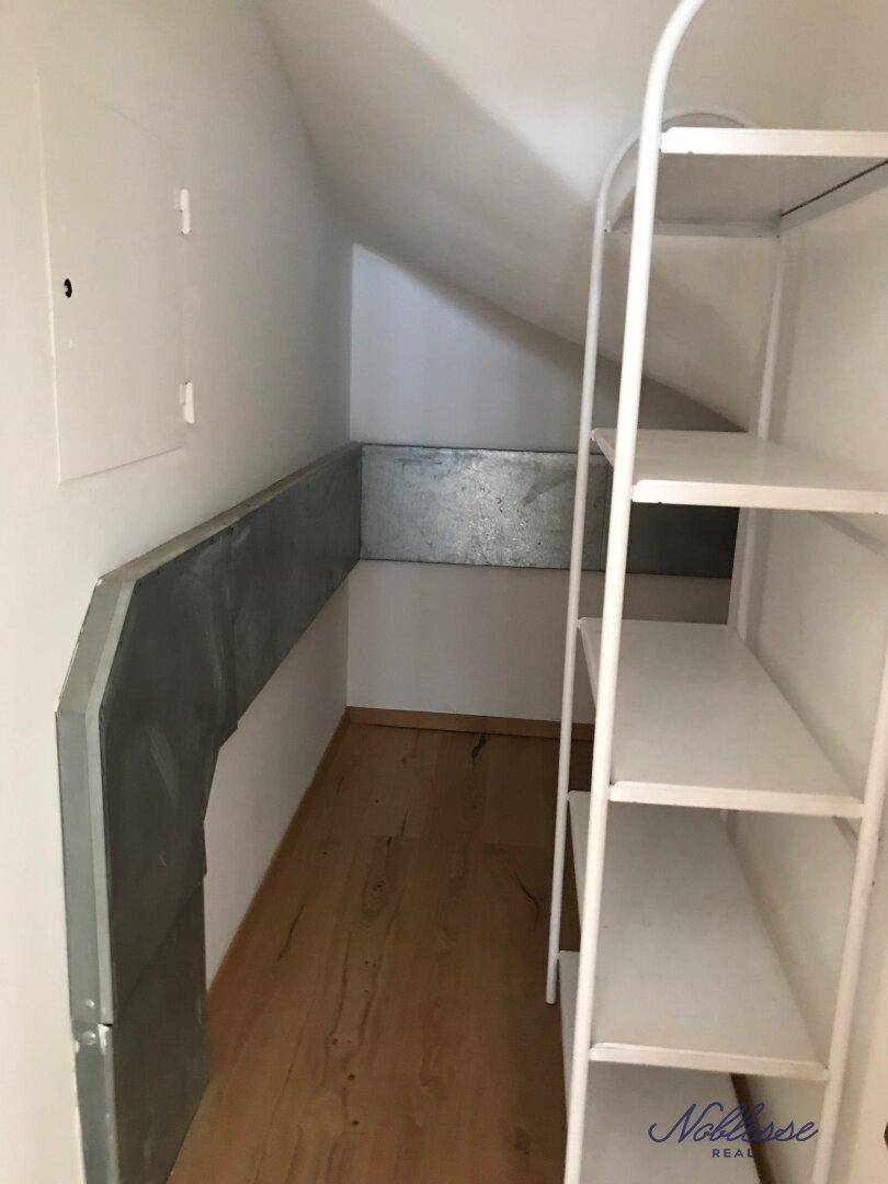 Praktischer Abstellraum unter der Dachschräge mit Regalen für zusätzlichen Stauraum.