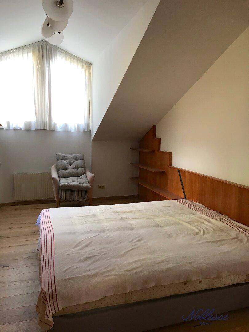Helles Schlafzimmer mit Holzboden, Dachschräge und großem Fenster.