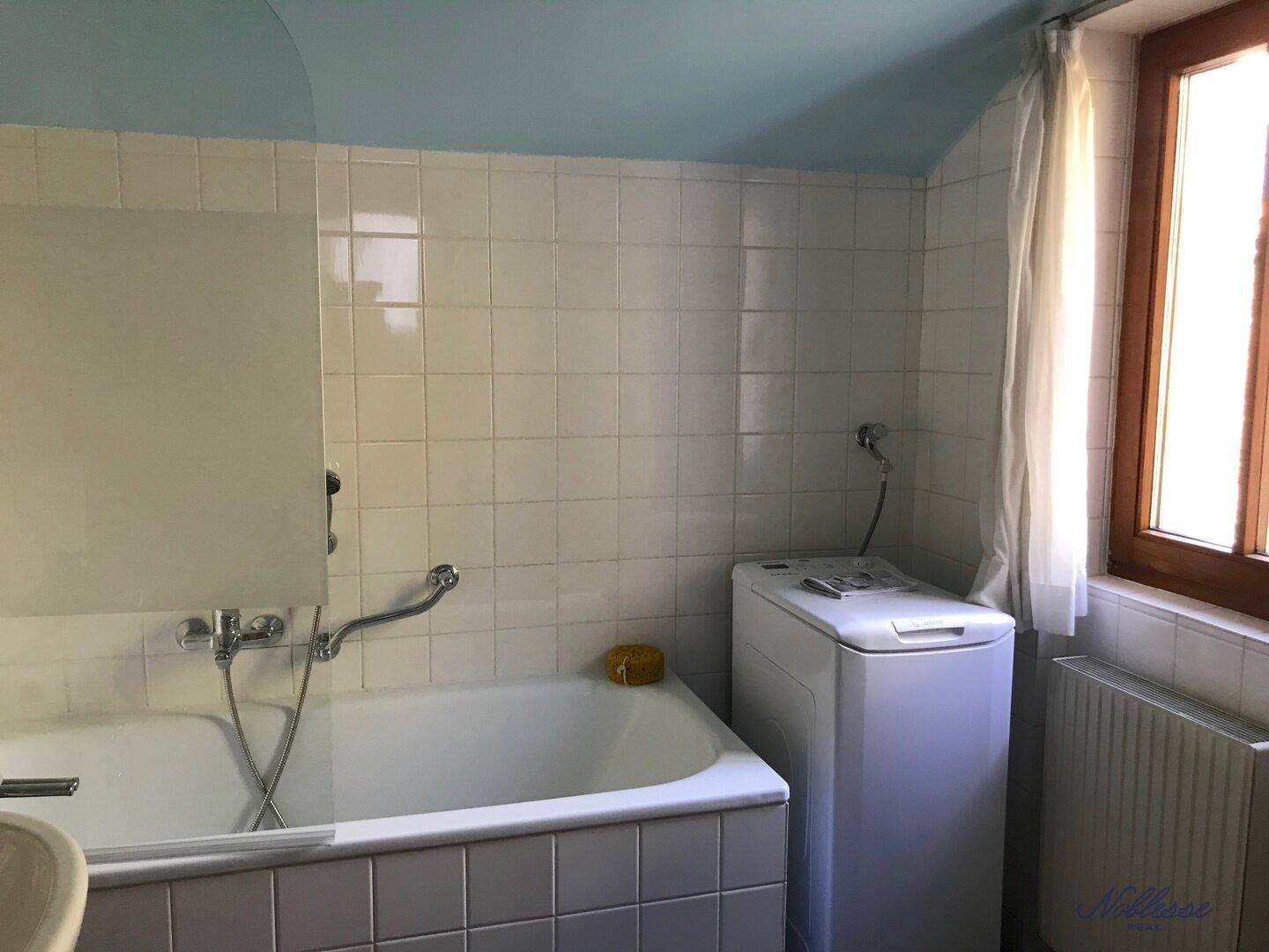 Badezimmer mit Badewanne, Waschmaschine und hellblauer Decke, bietet Komfort.