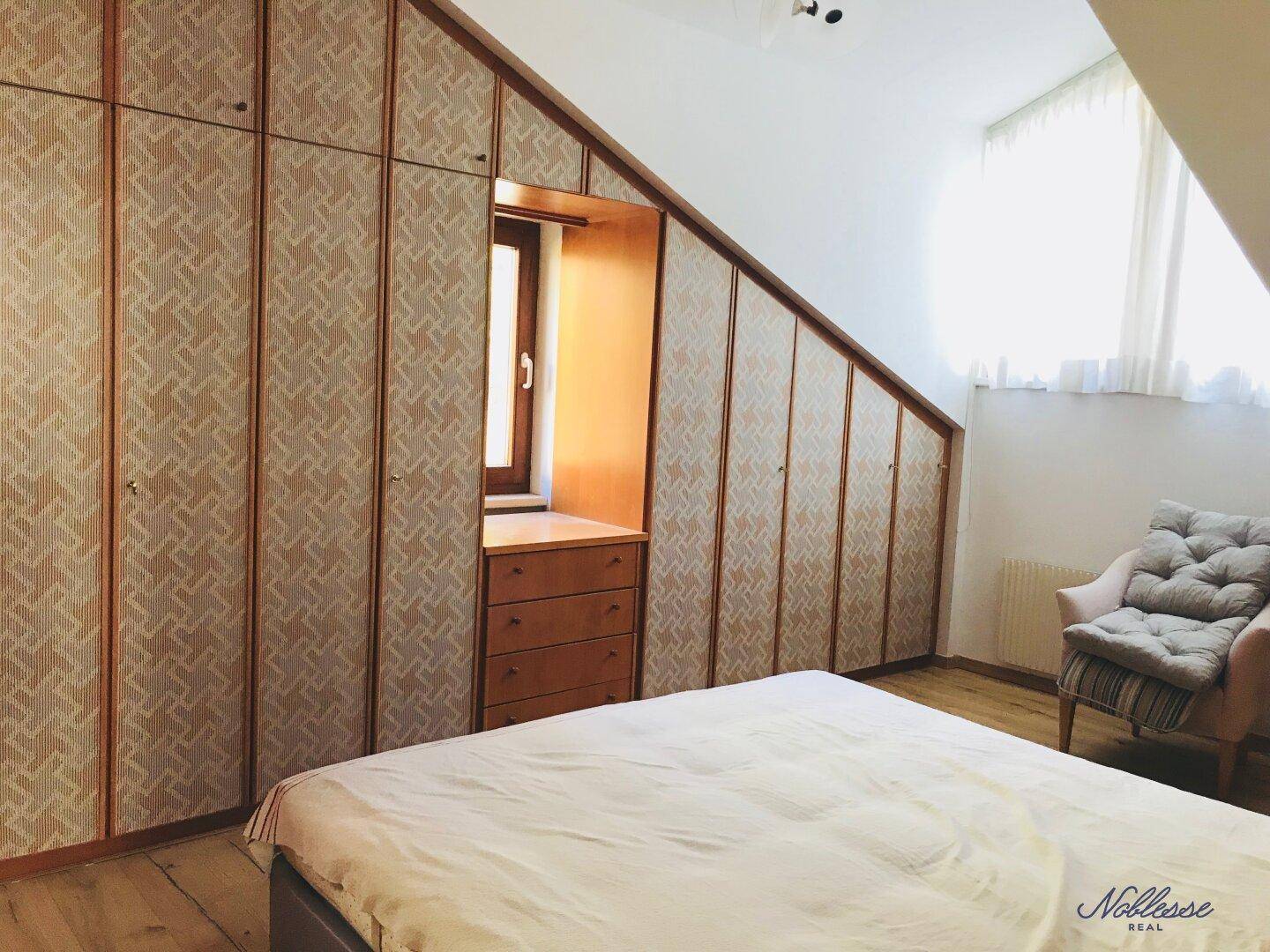 Schlafzimmer mit maßgefertigten Einbauschränken unter der Dachschräge und Holzboden.