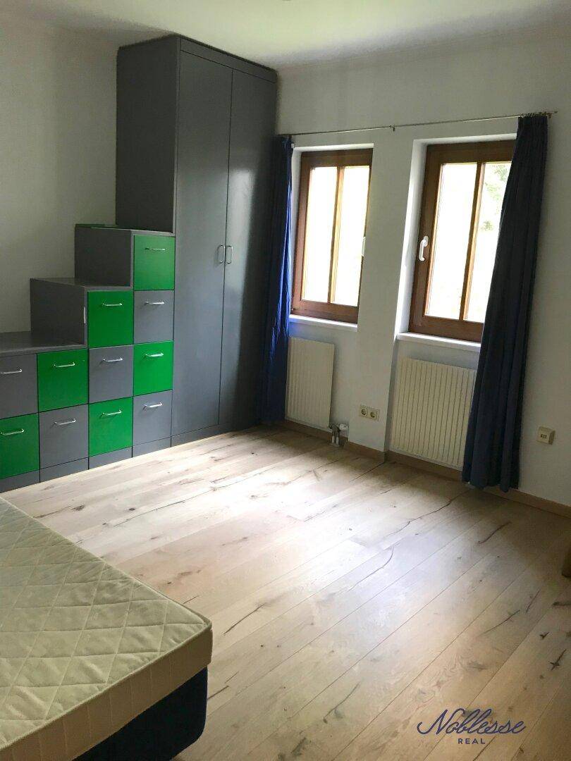 Kinderzimmer oder Gästezimmer mit Holzboden und farbenfrohen Aufbewahrungsmöbeln.