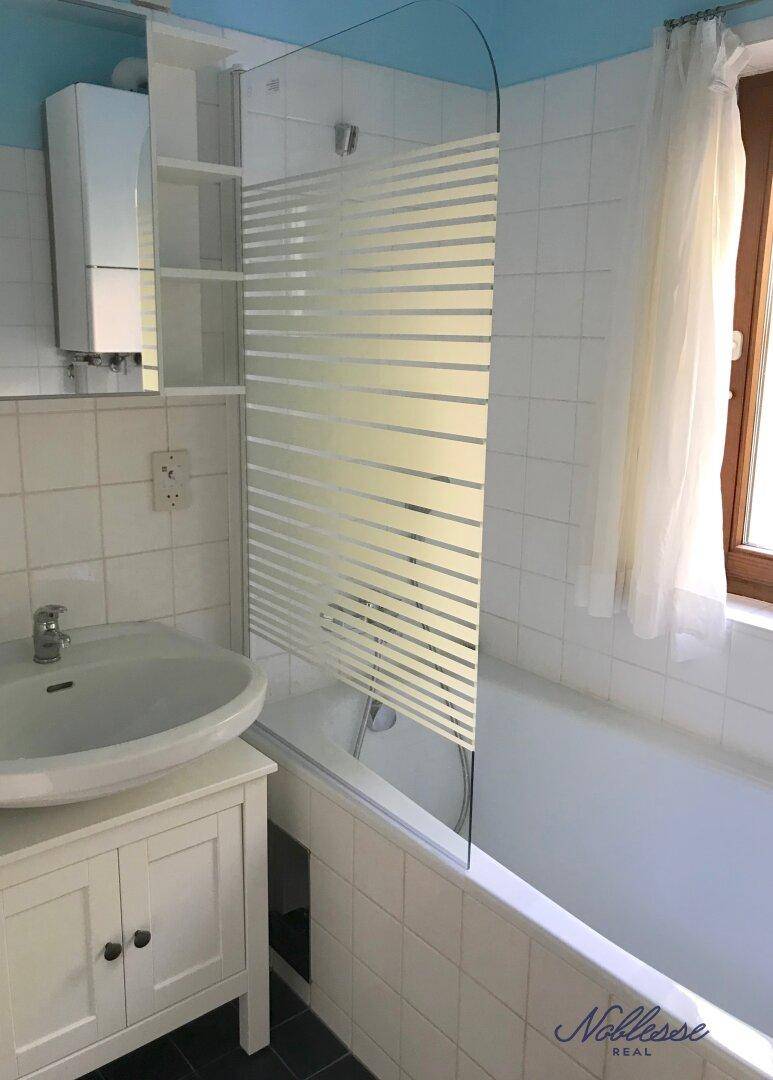 Badezimmer mit Badewanne, Duschabtrennung und Fenster für gute Belüftung.