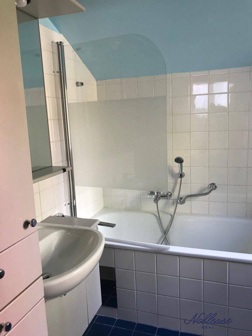 Badezimmer mit Badewanne, Duschabtrennung und Waschbecken, funktional und hell.