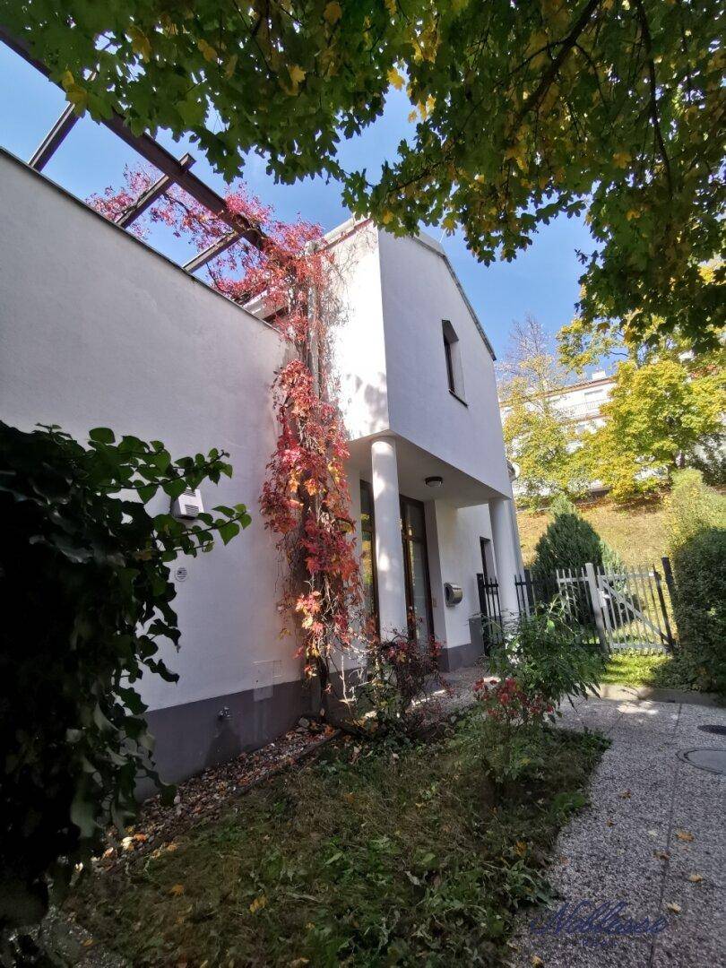 Attraktive Hausfassade mit üppiger Begrünung und gepflegtem Vorgarten.