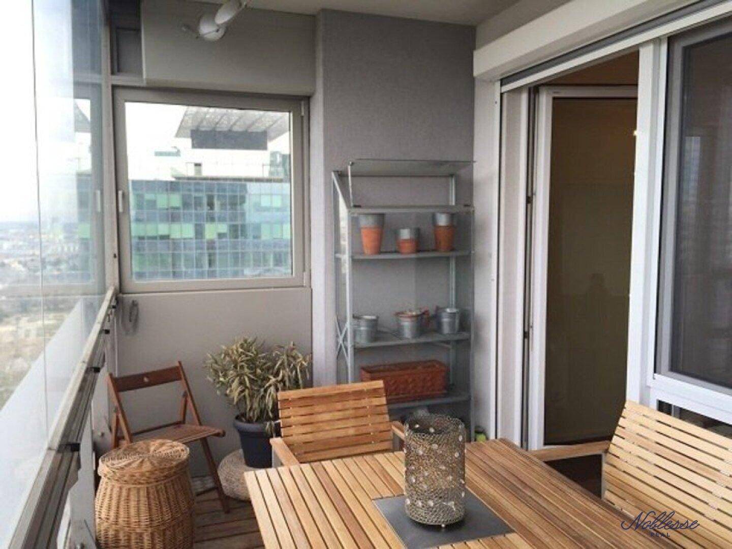 Gemütlicher verglaster Balkon mit Holztisch und Stühlen, ideal für entspannte Stunden.