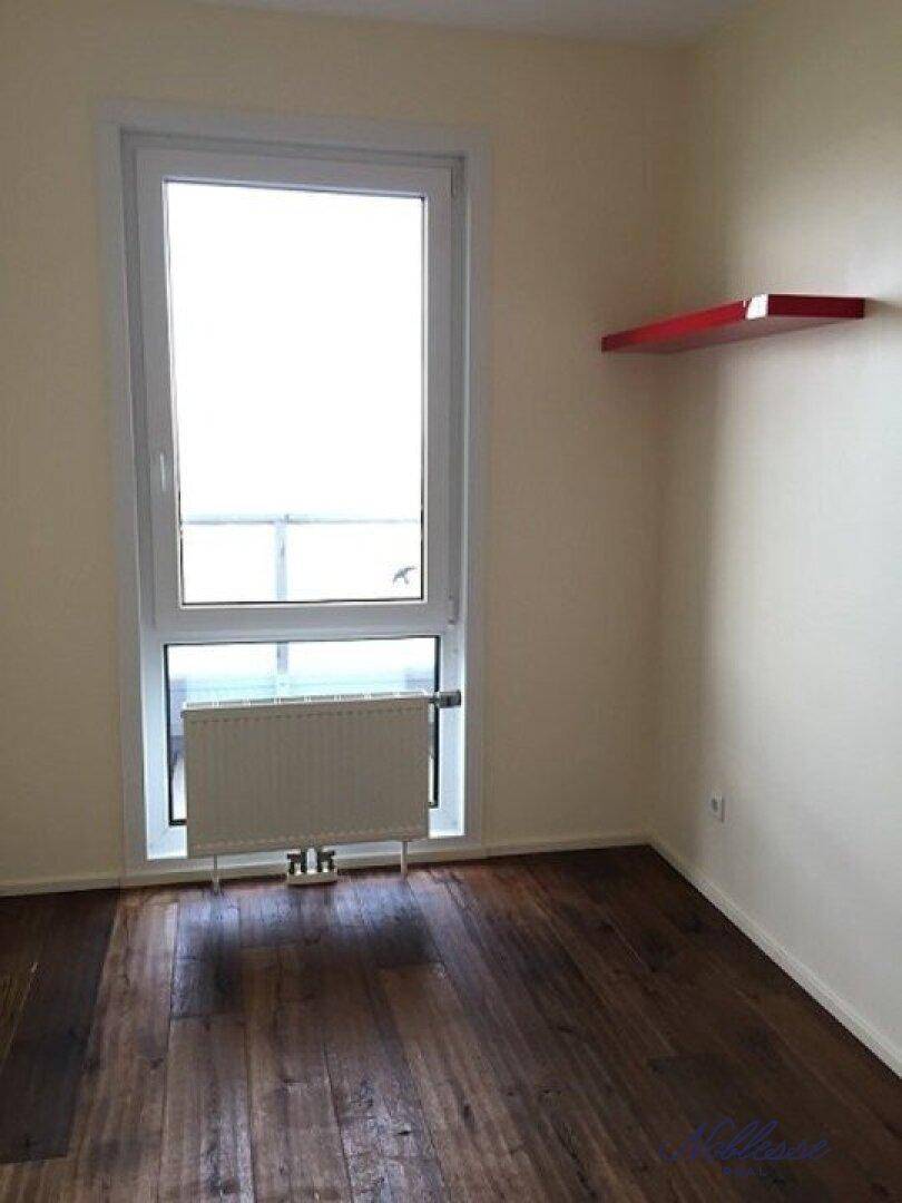 Heller Raum mit Holzboden, großem Fenster und Heizkörper, vielseitig nutzbar.