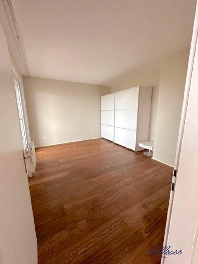 Helles Schlafzimmer mit Holzboden und einem großen weißen Einbauschrank.