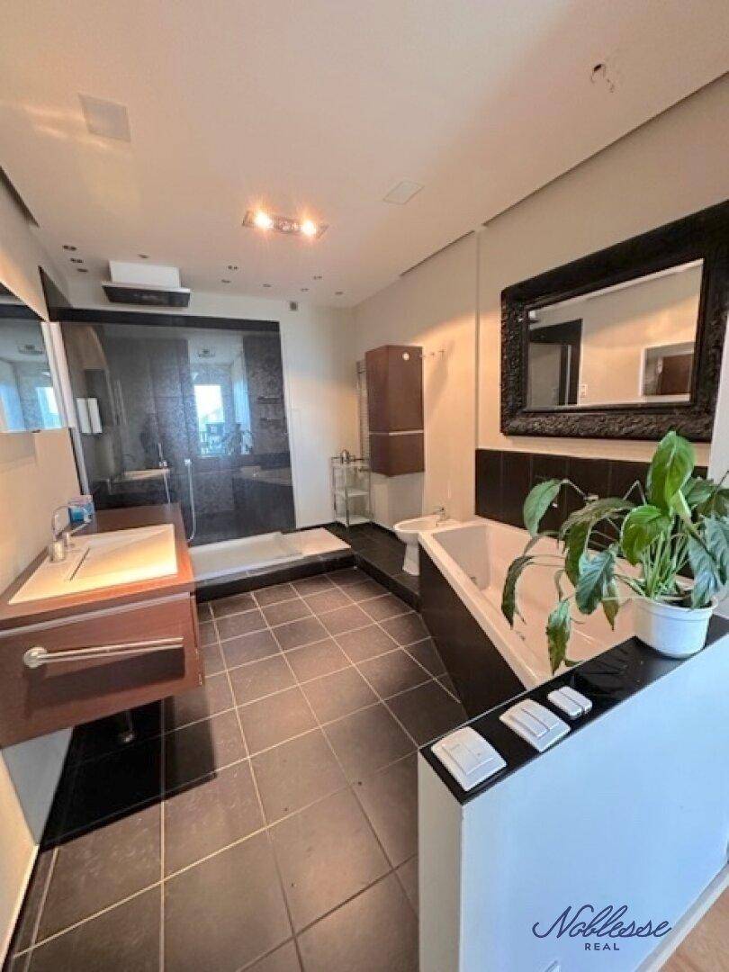 Modernes Badezimmer mit dunklen Fliesen, Badewanne, begehbarer Dusche und Bidet.