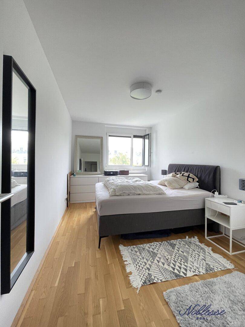 Helles Schlafzimmer mit Doppelbett, Holzboden und großem Fenster für viel Tageslicht.