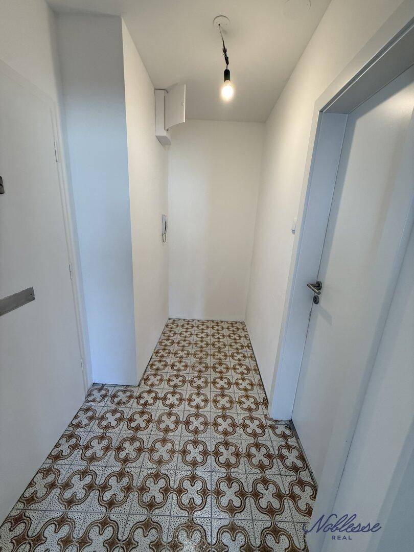 Eingangsbereich mit gemustertem Fliesenboden und weißen Wänden, bietet Platz für Garderobe.