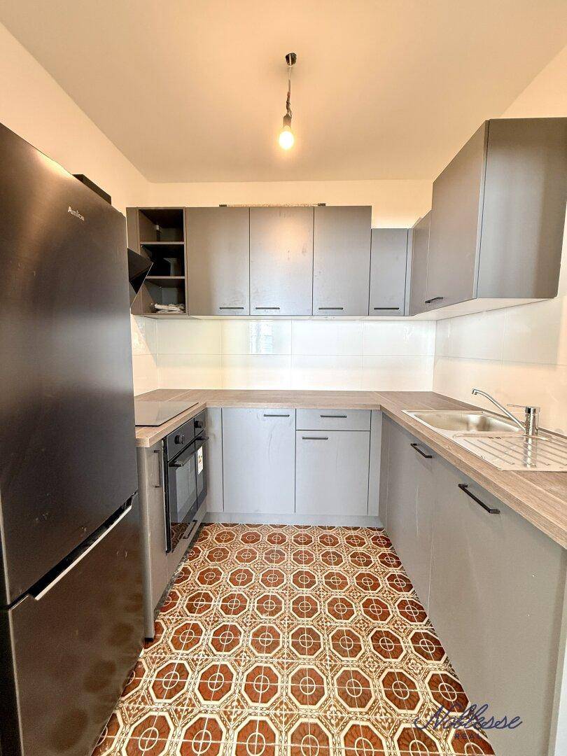 Moderne Küche mit grauen Schränken, Holz-Arbeitsplatte und gemustertem Fliesenboden.