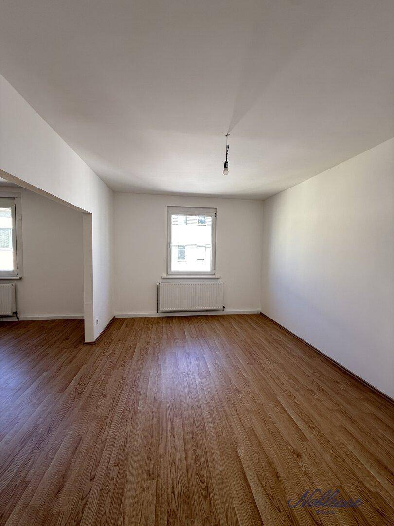 Lichtdurchfluteter Wohnraum mit Laminatboden und einem Fenster, ideal für eine moderne Einrichtung.