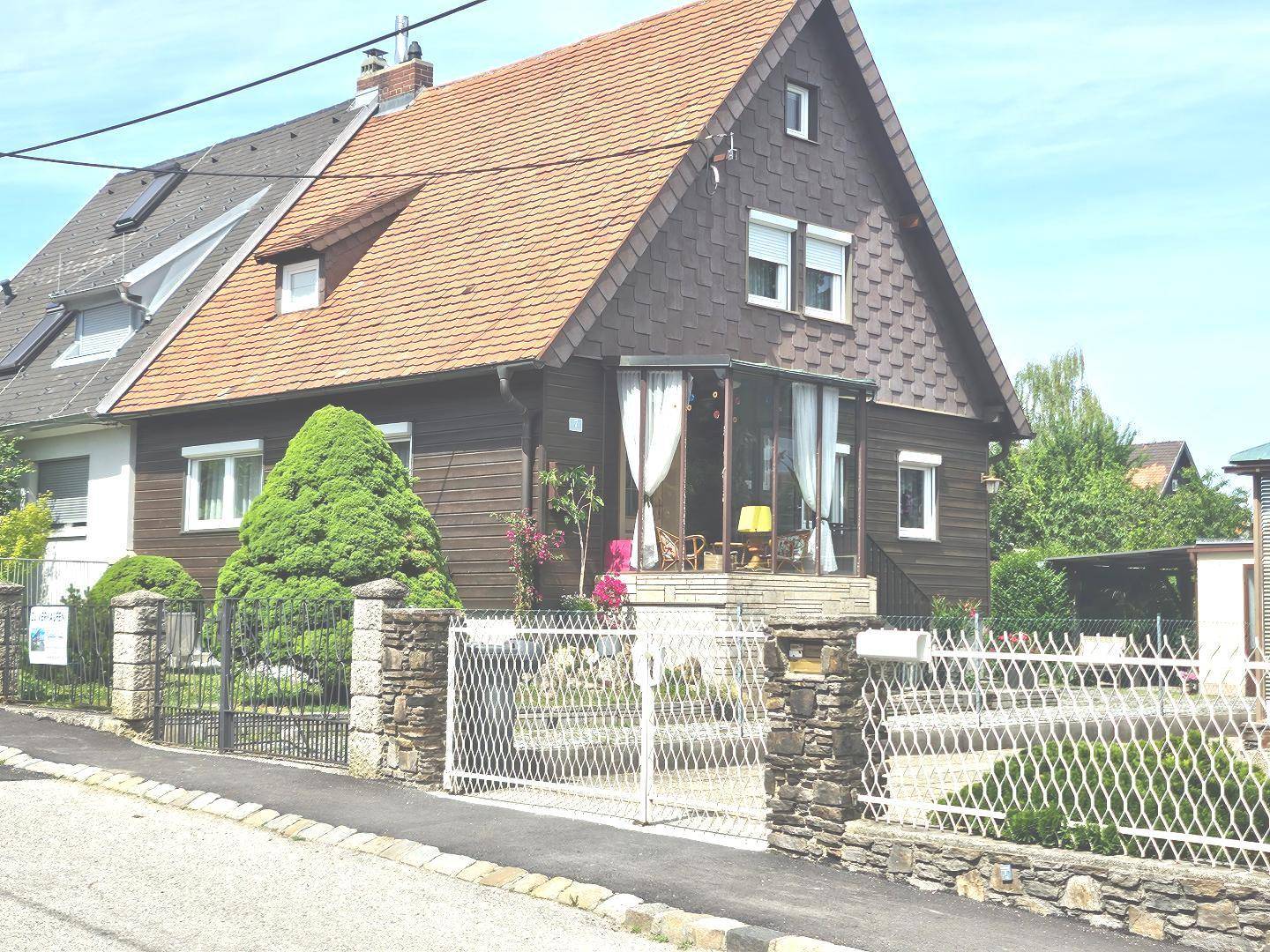 Vorderansicht des Hauses mit Satteldach, Vorgarten und einem Zaun zur Straße.