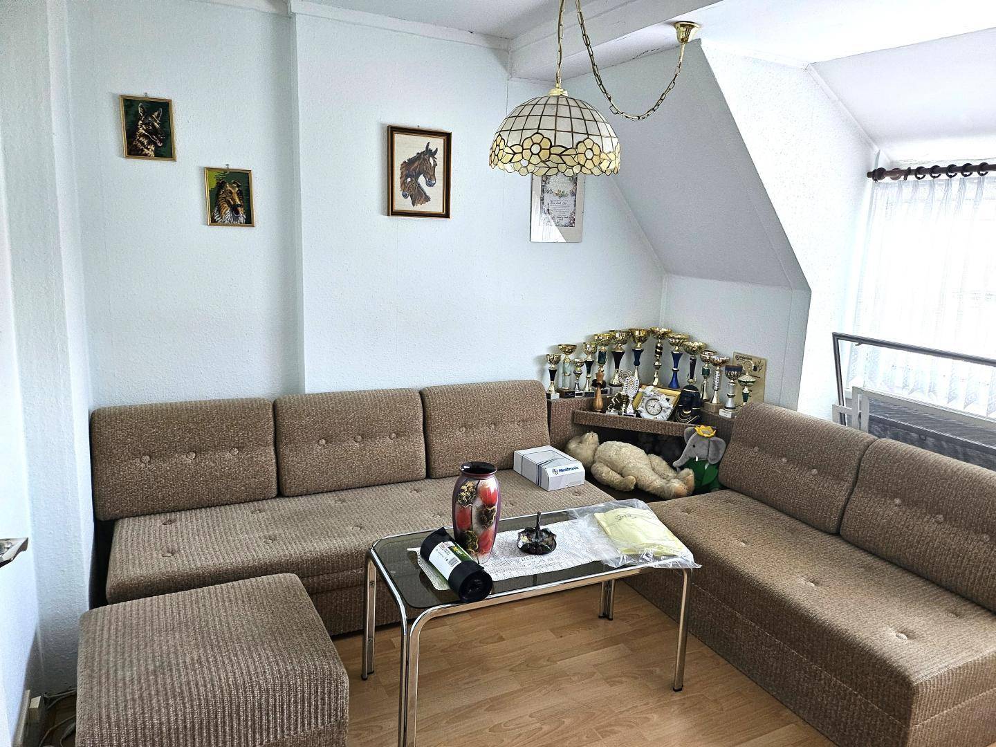 Gemütliches Wohnzimmer im Dachgeschoss mit Ecksofa und dekorativen Elementen.
