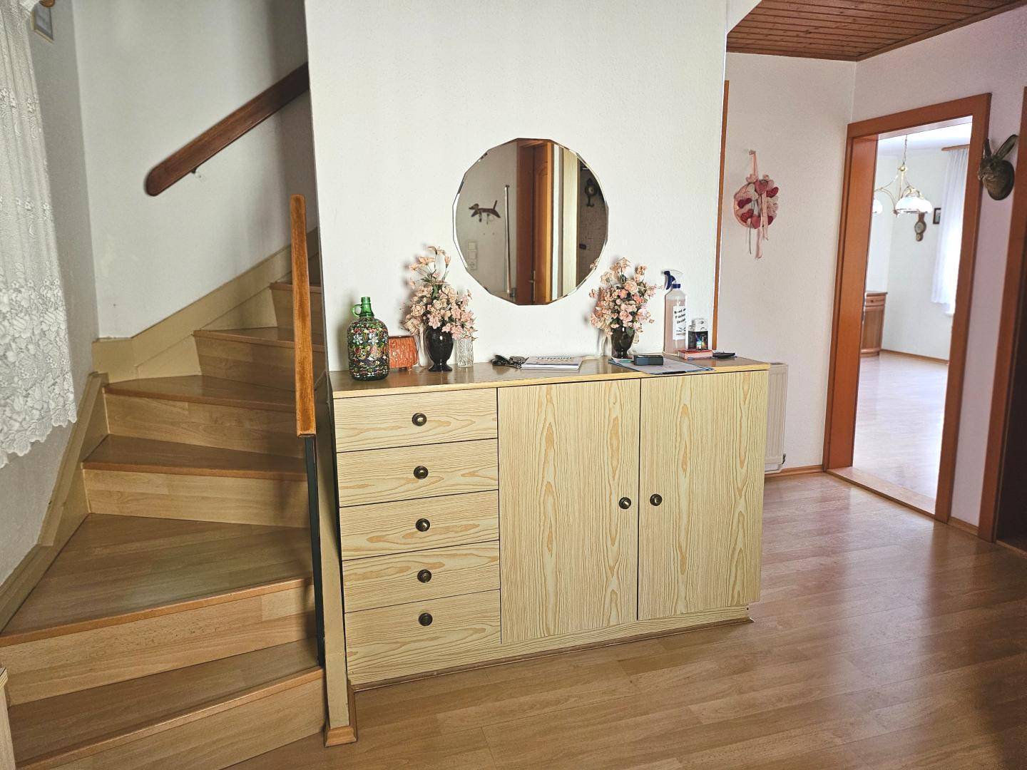 Heller Flur mit Holztreppe, einem Spiegel und einem praktischen Holzschrank.