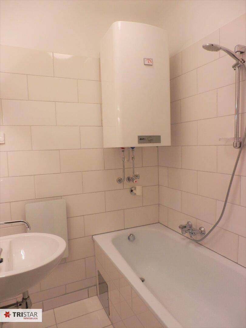 Funktionales Badezimmer mit Badewanne, Dusche, Waschbecken und weißen Wandfliesen.
