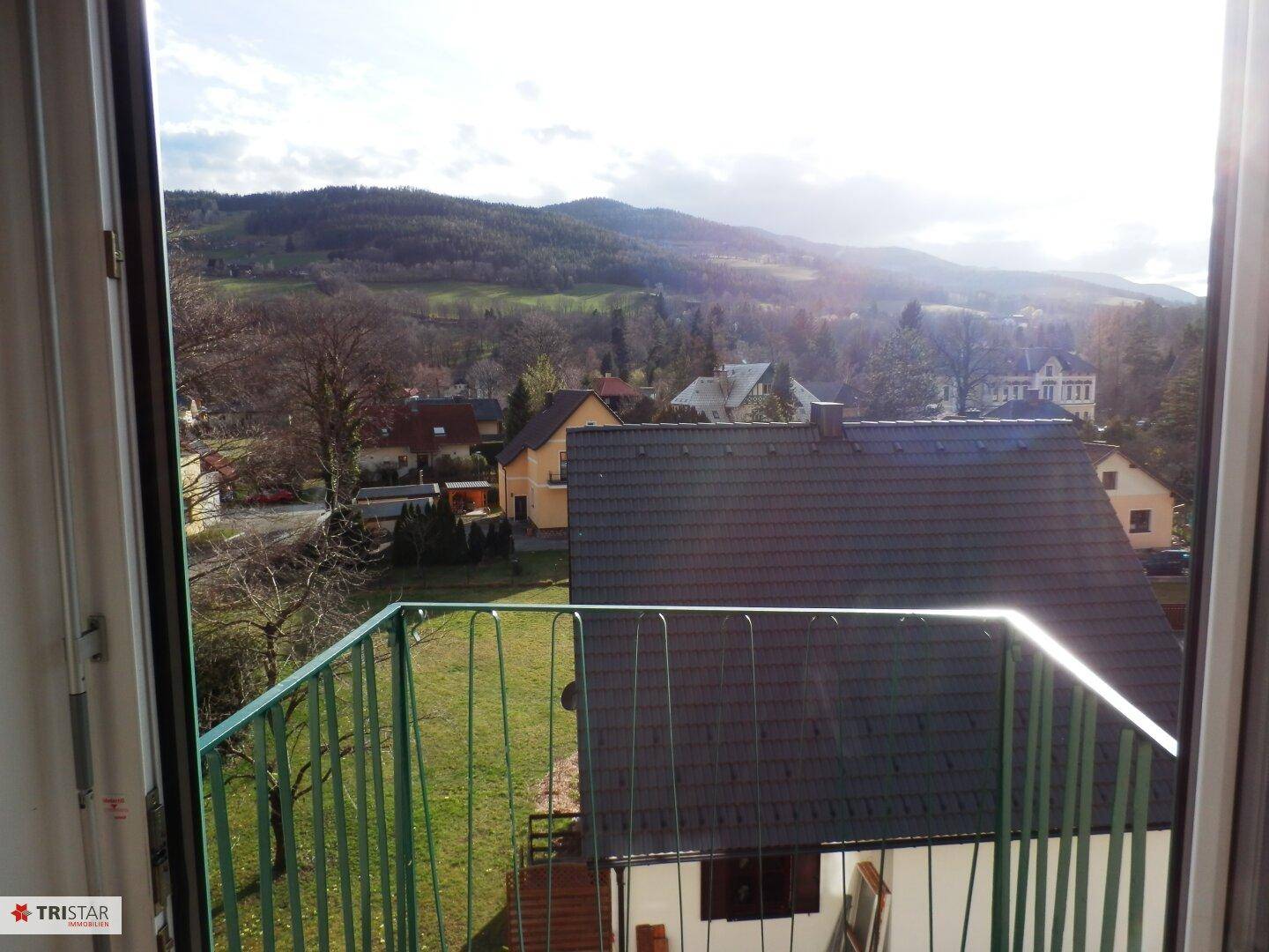 Weitblick aus dem Fenster auf die grüne Hügellandschaft und die Dächer der Nachbarhäuser.